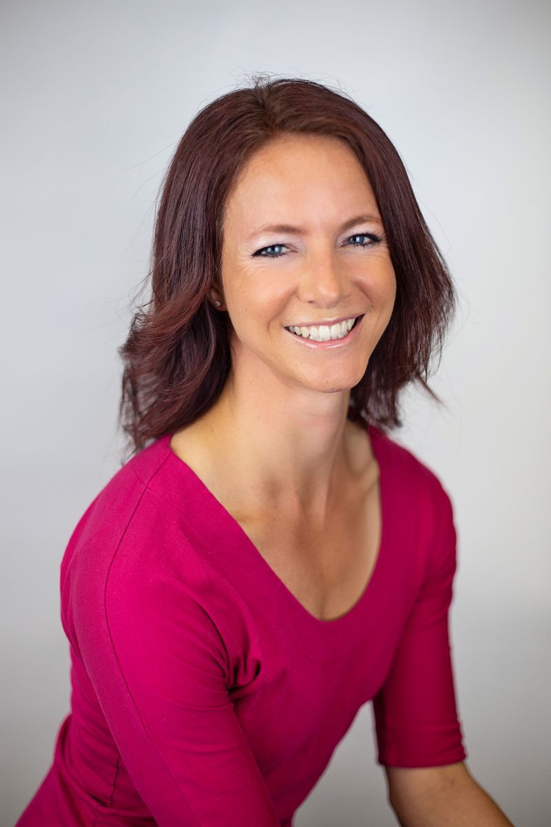 A woman in a pink shirt is smiling for the camera.