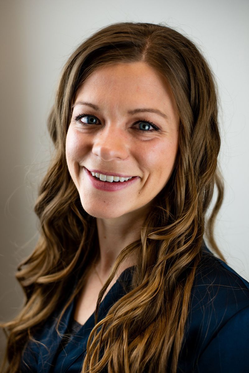 A woman with long brown hair is smiling for the camera.