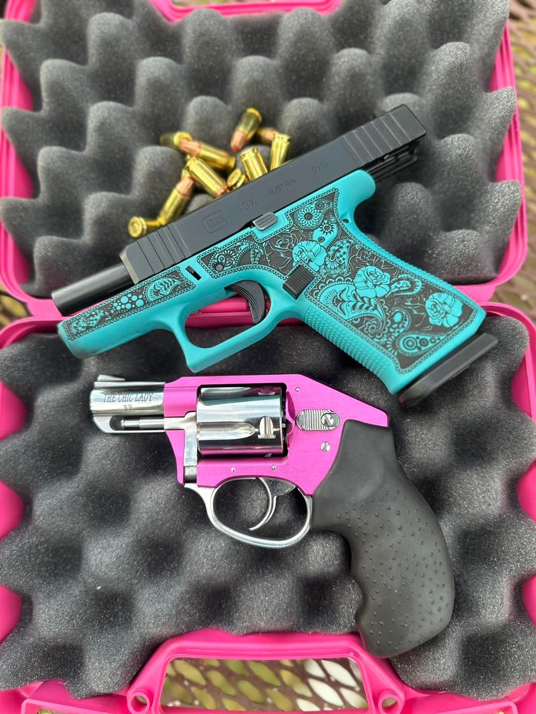 Two handguns in a pink case: a teal and black semi-automatic and a pink revolver.