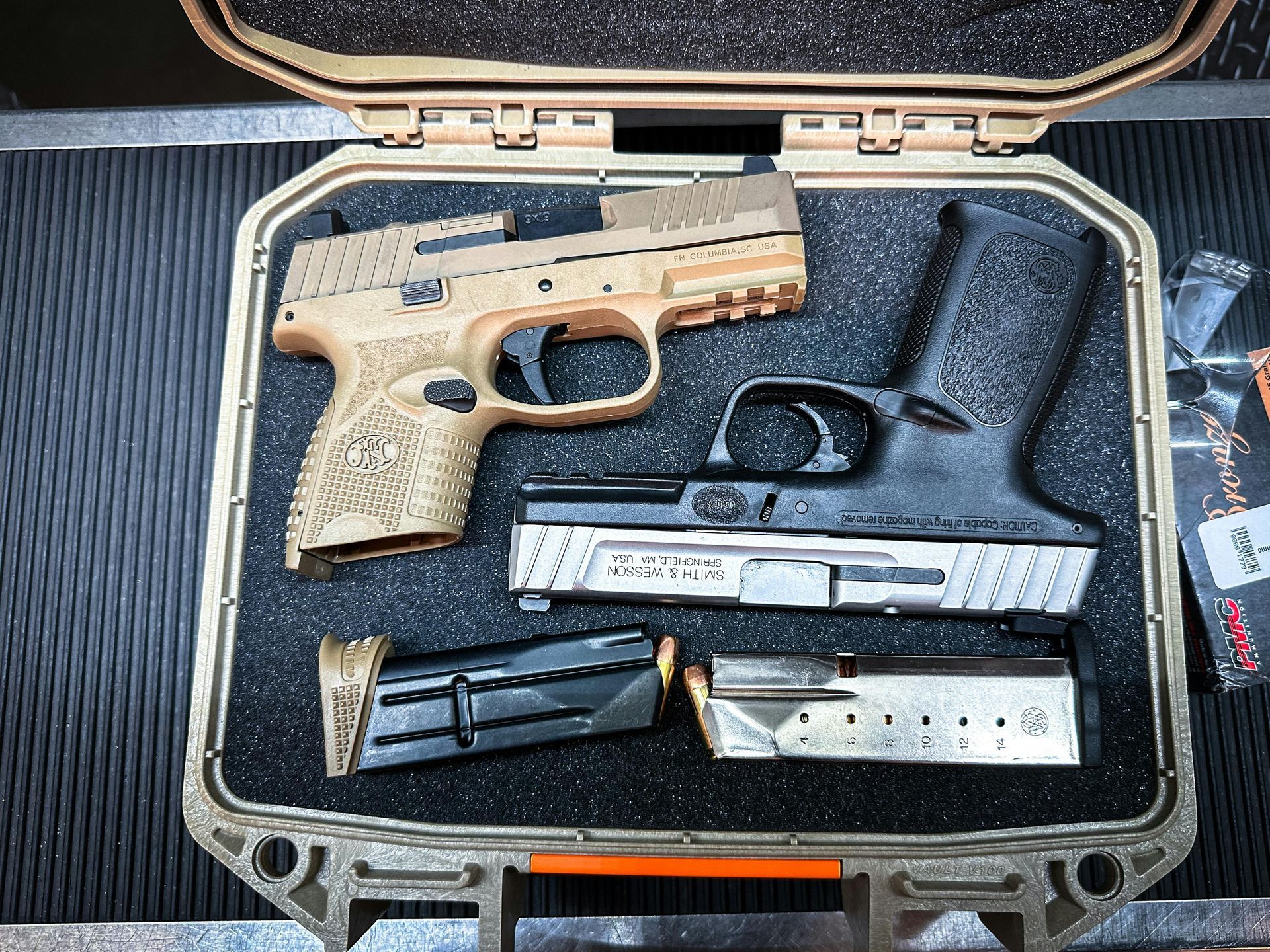 Two handguns and two magazines inside a tan case. One gun is tan, the other black.