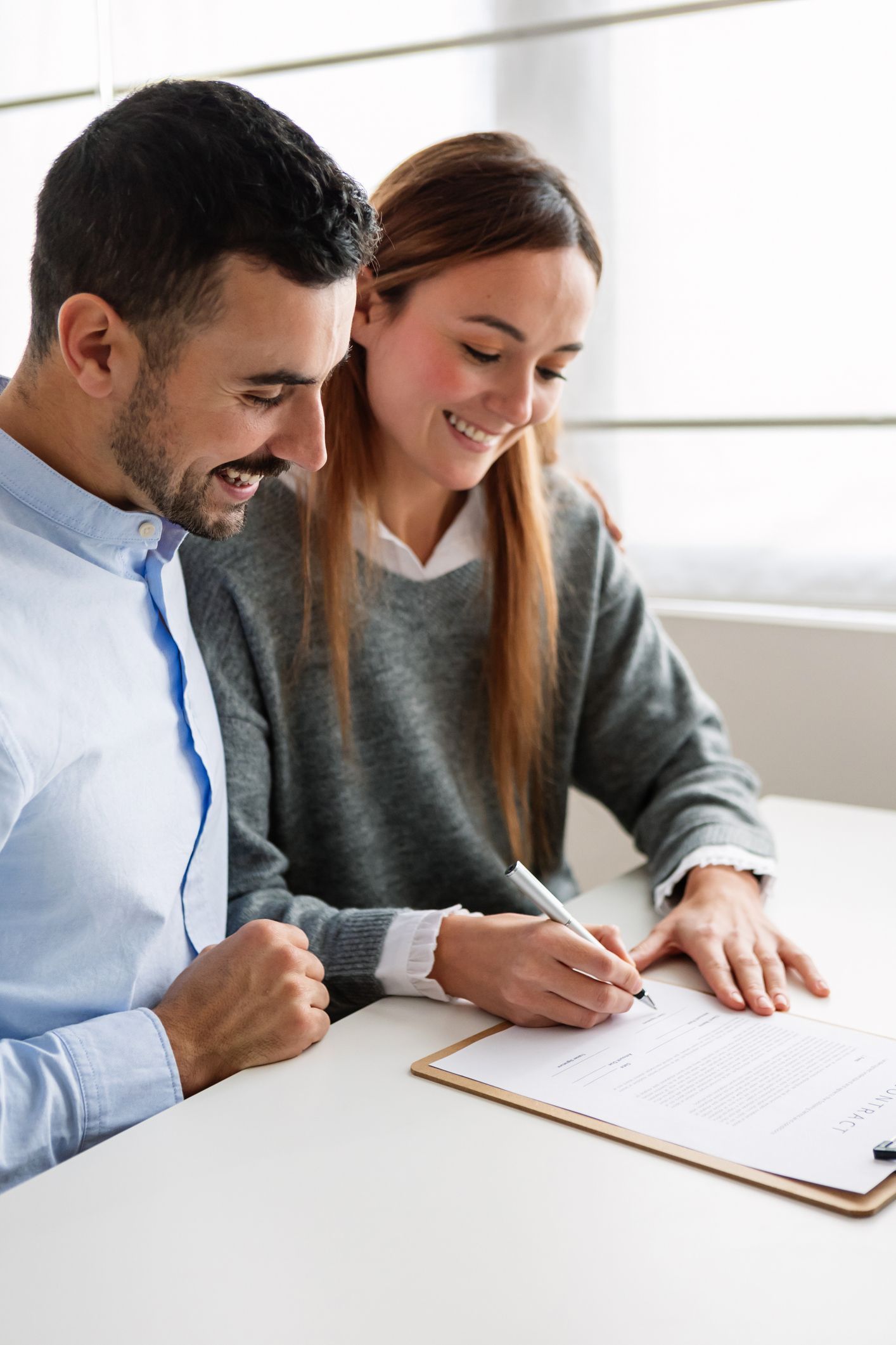 A man and a woman are sitting at a table signing a document. A man and a woman are sitting at a table signing a document.