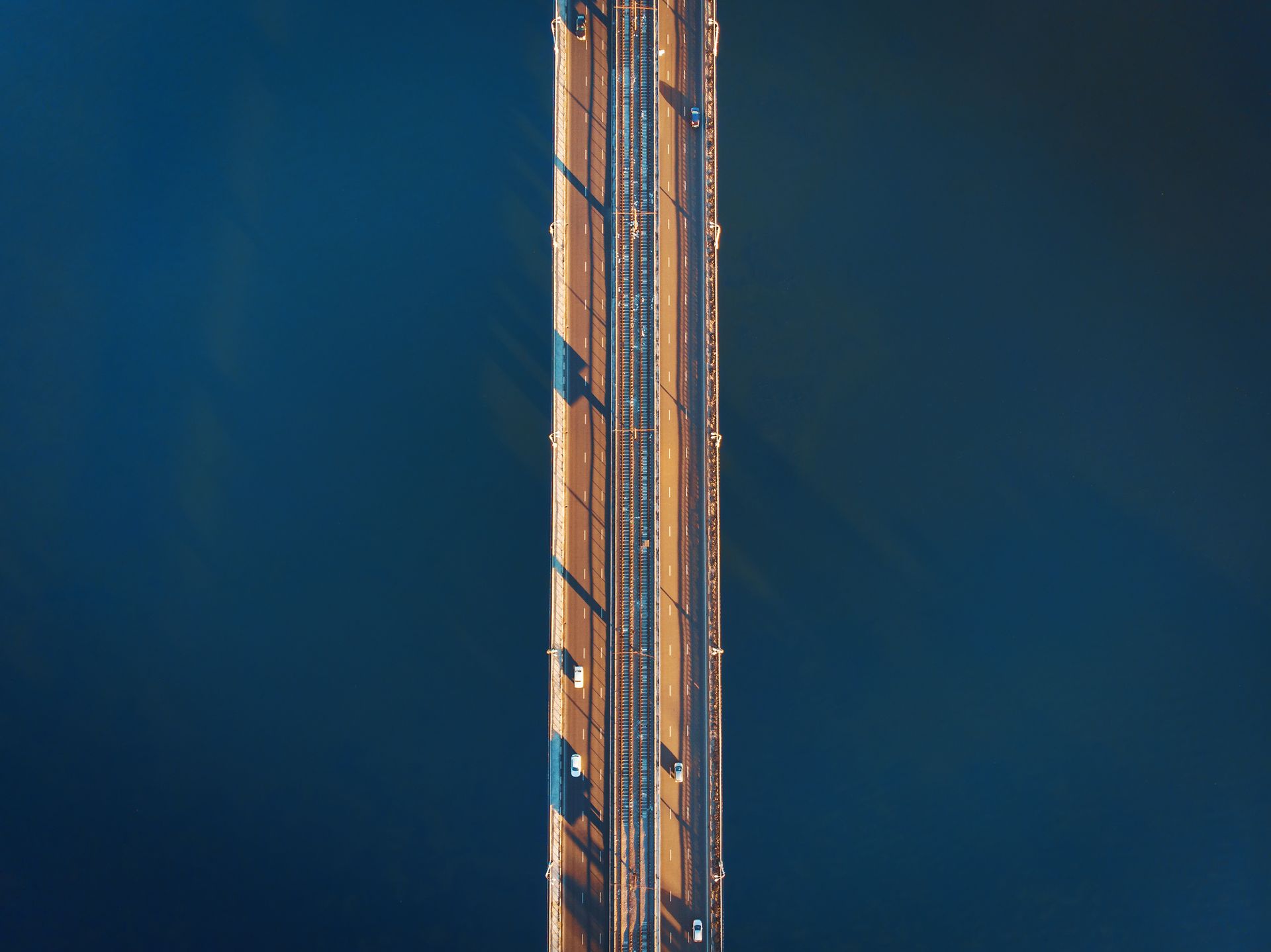 A man wearing a black vest and a sweater is smiling for the camera.