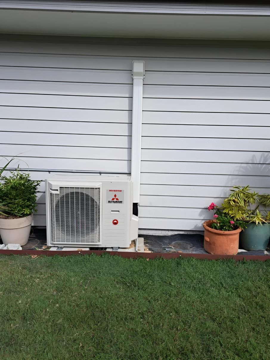 A Red and Black Solar Inverter is Mounted on the Side of a Building — Reilly Electrical Services in Yandina, QLD