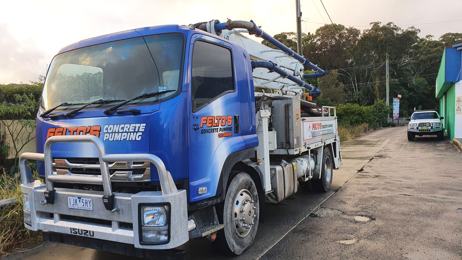 Blue Felto’s boom pump truck parked on a street— Felto's Concrete Line Pumping in Coffs Harbour, NSW
