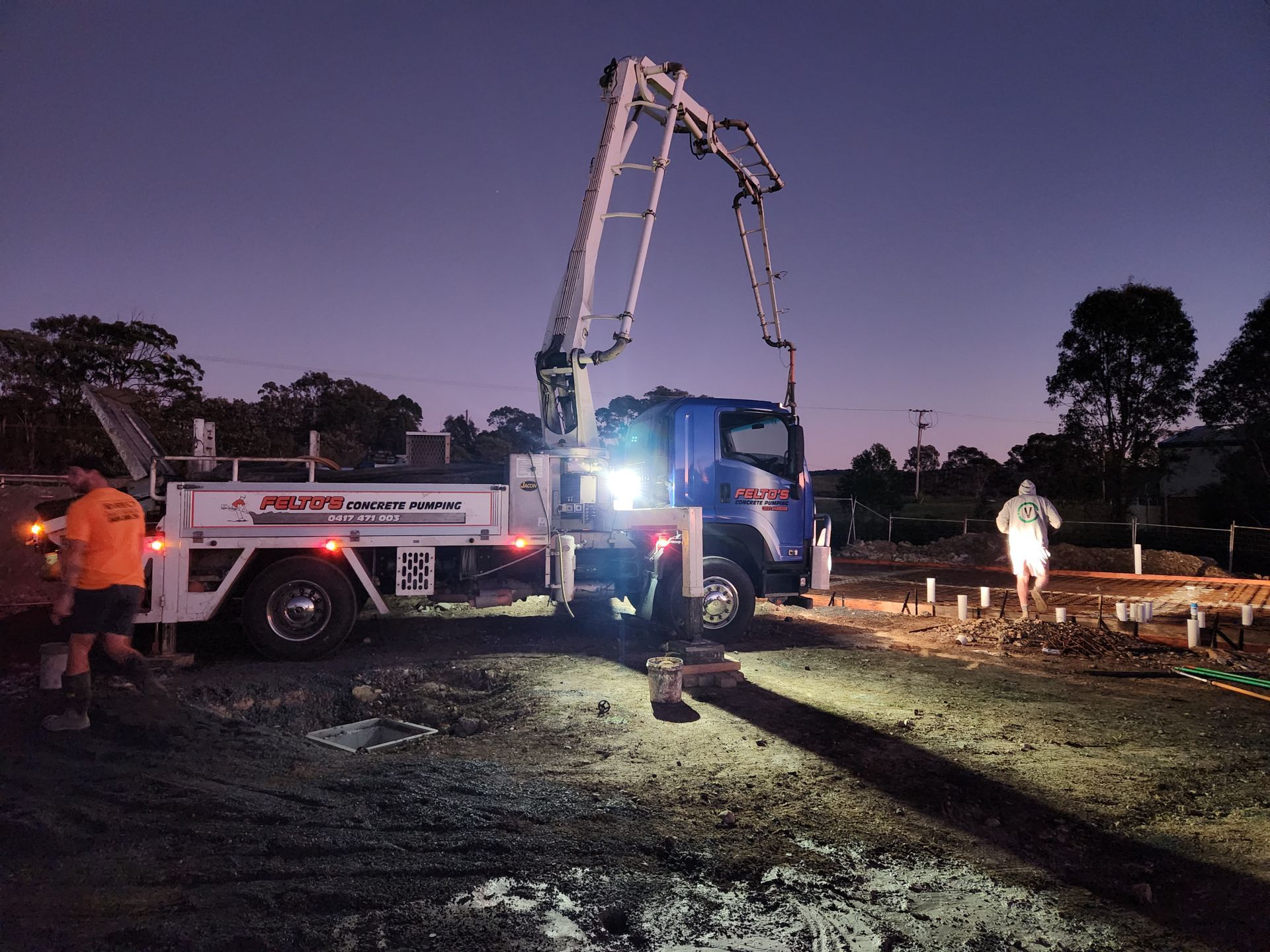 Felto’s boom pump operating at night with workers on site — Felto's Concrete Line Pumping in Coffs Harbour, NSW.
