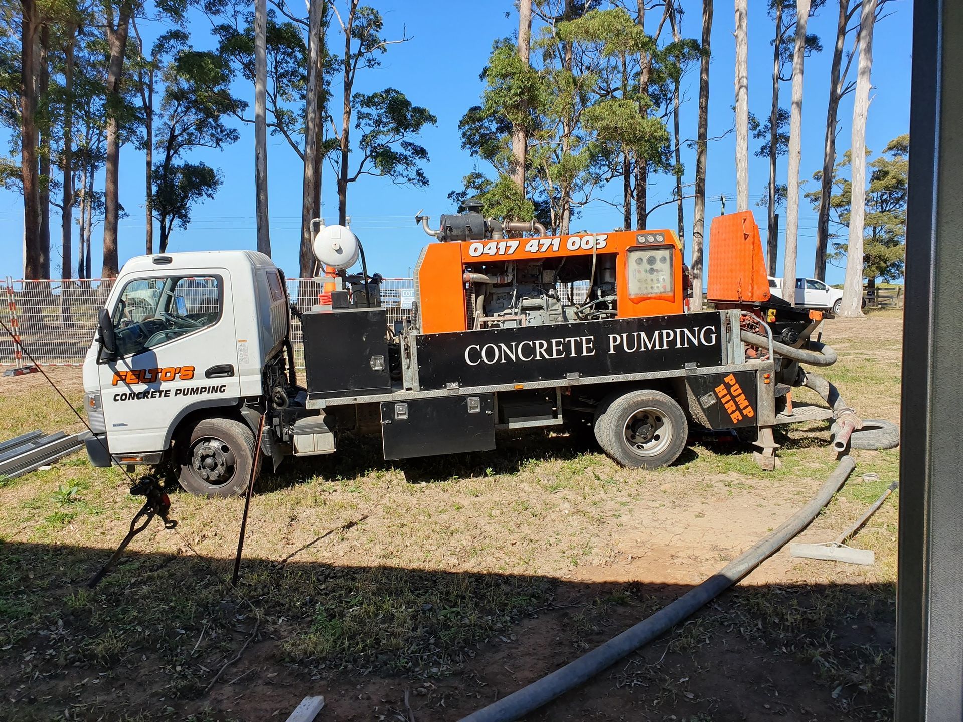 Concrete pumping truck parked on grassy site near tall trees. — Felto's Concrete Line Pumping in Coffs Harbour, NSW
