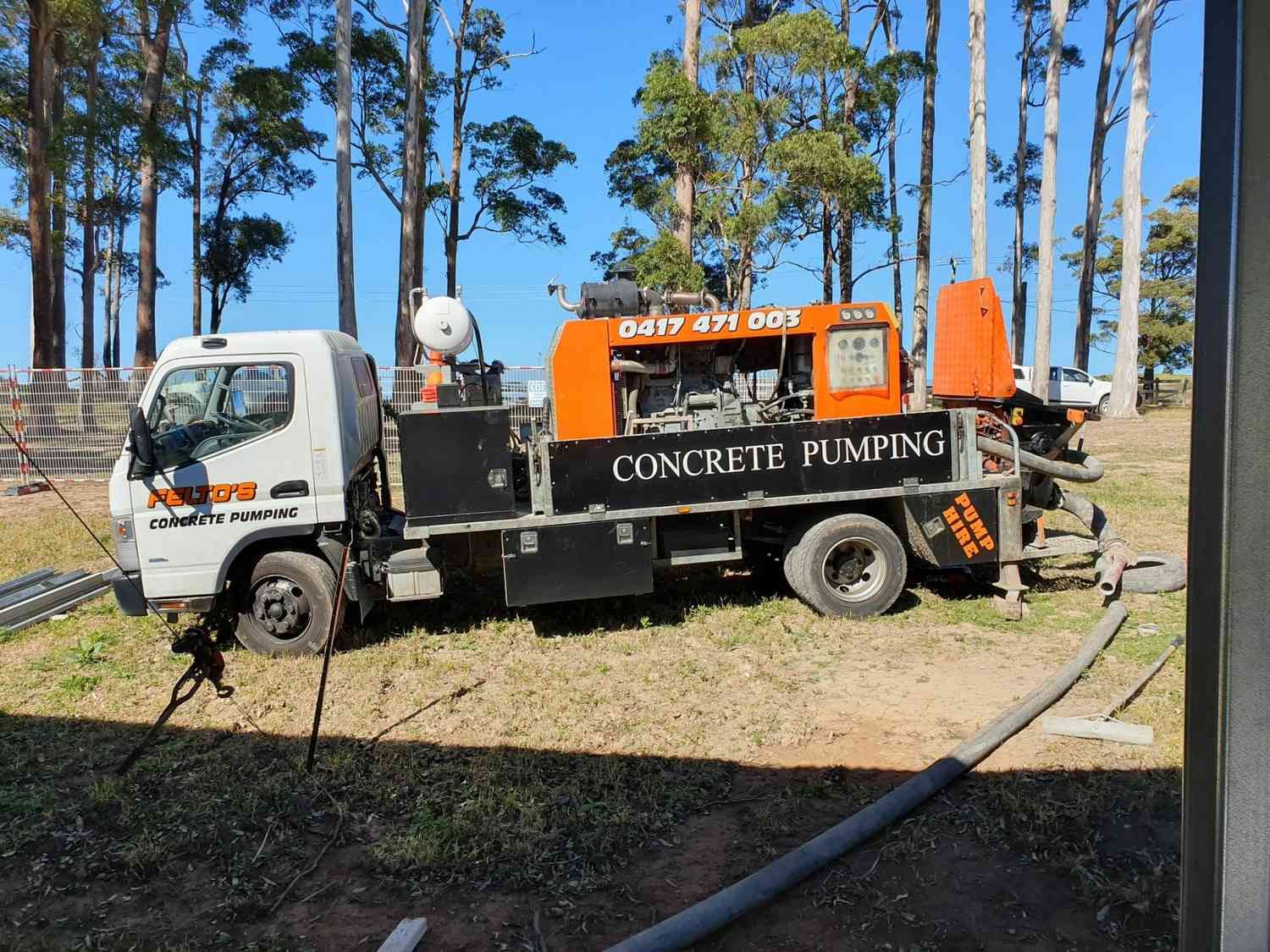A Concrete Pumping Truck is Parked in a Field With Trees in the Background — Felto's Concrete Line Pumping in Bellingen, NSW