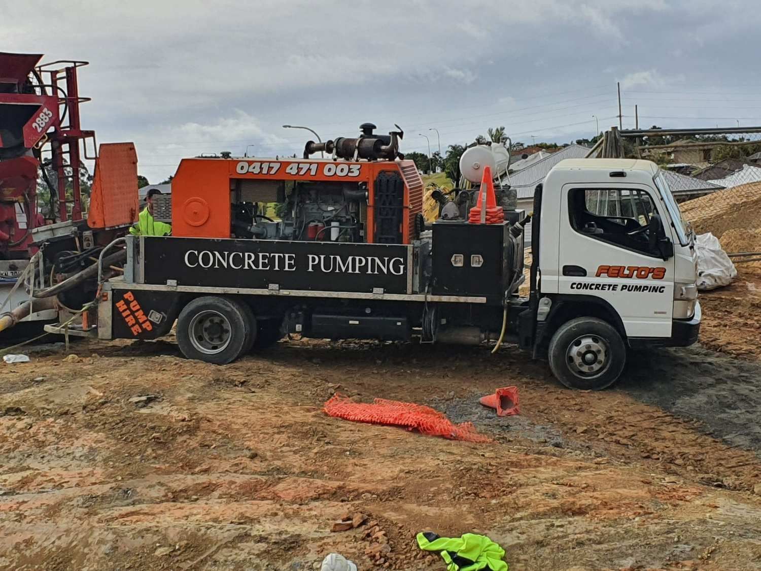 A Concrete Pumping Truck is Parked in a Dirt Field — Felto's Concrete Line Pumping in Coffs Harbour, NSW