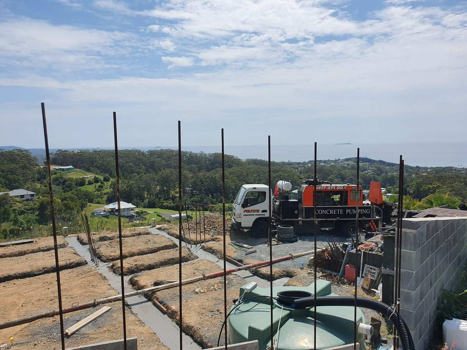 Concrete pumping truck parked at a hillside construction site with ocean view.— Felto's Concrete Line Pumping in Coffs Harbour, NSW