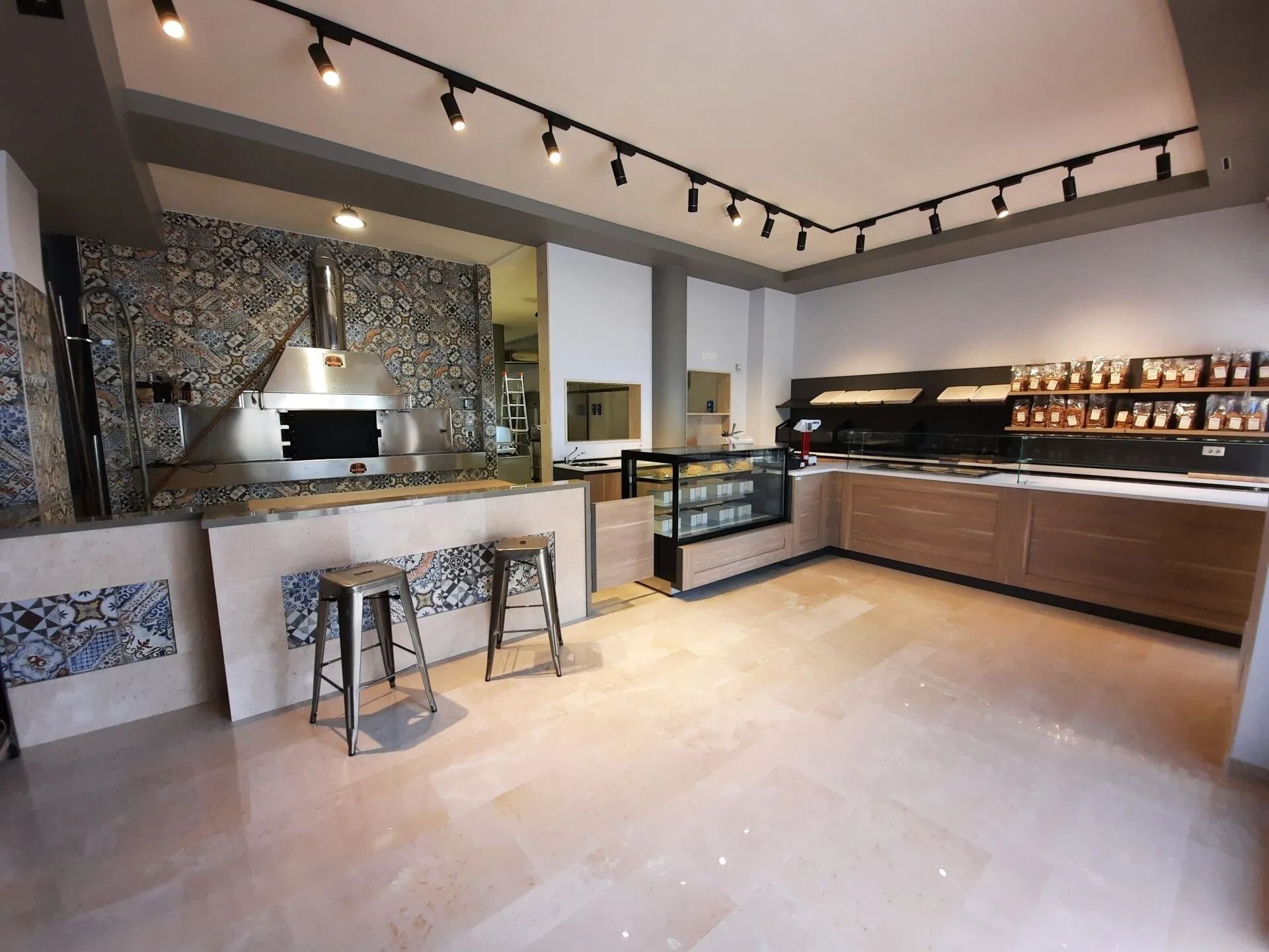 Cucina moderna con isola centrale, sgabelli, mobili in legno e faretti a binario, vista da un ampio open space.