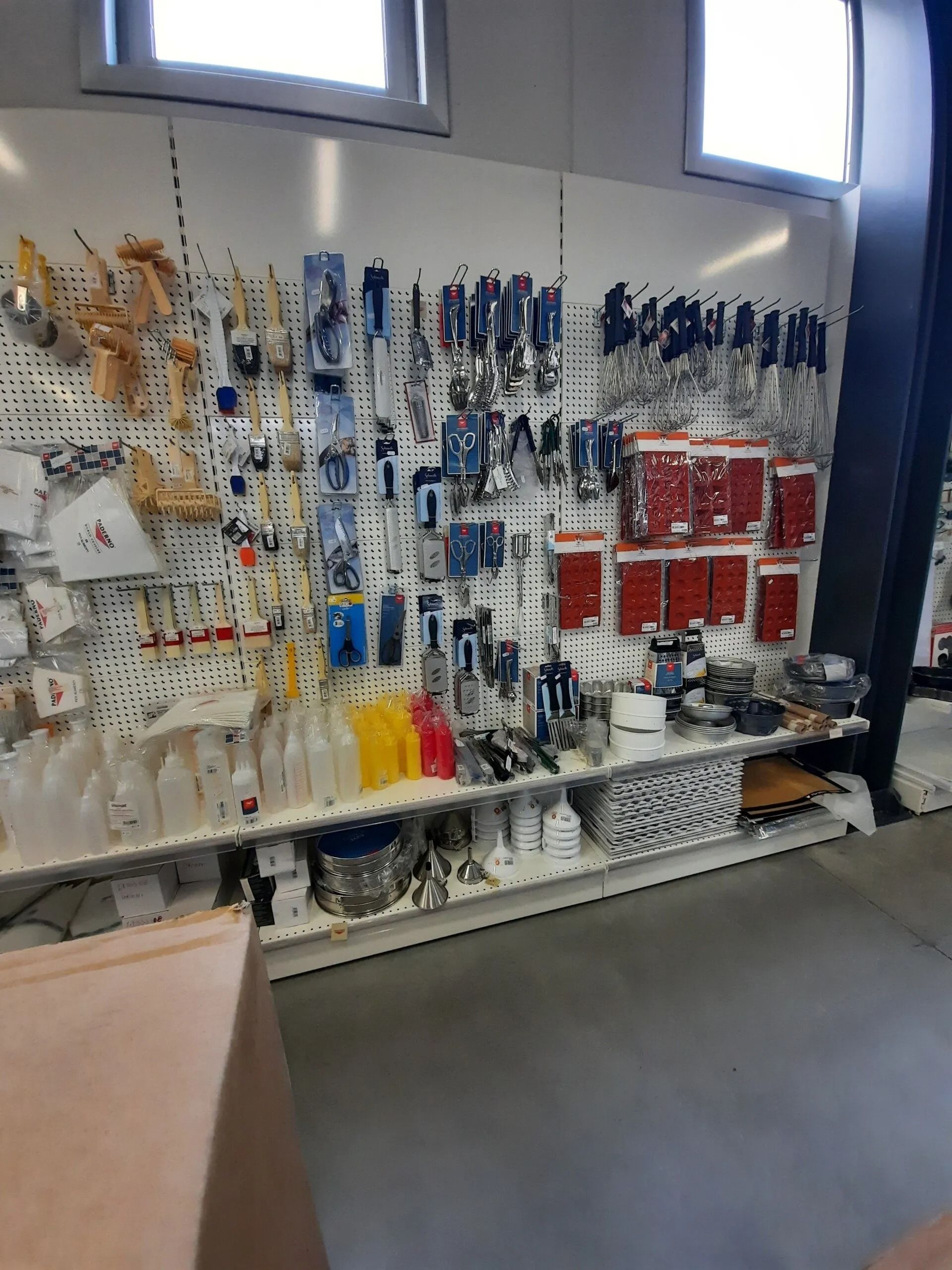 Corridoio del negozio con una parete di prodotti confezionati, per lo più articoli blu e rossi, esposti su scaffali sotto le vetrine.