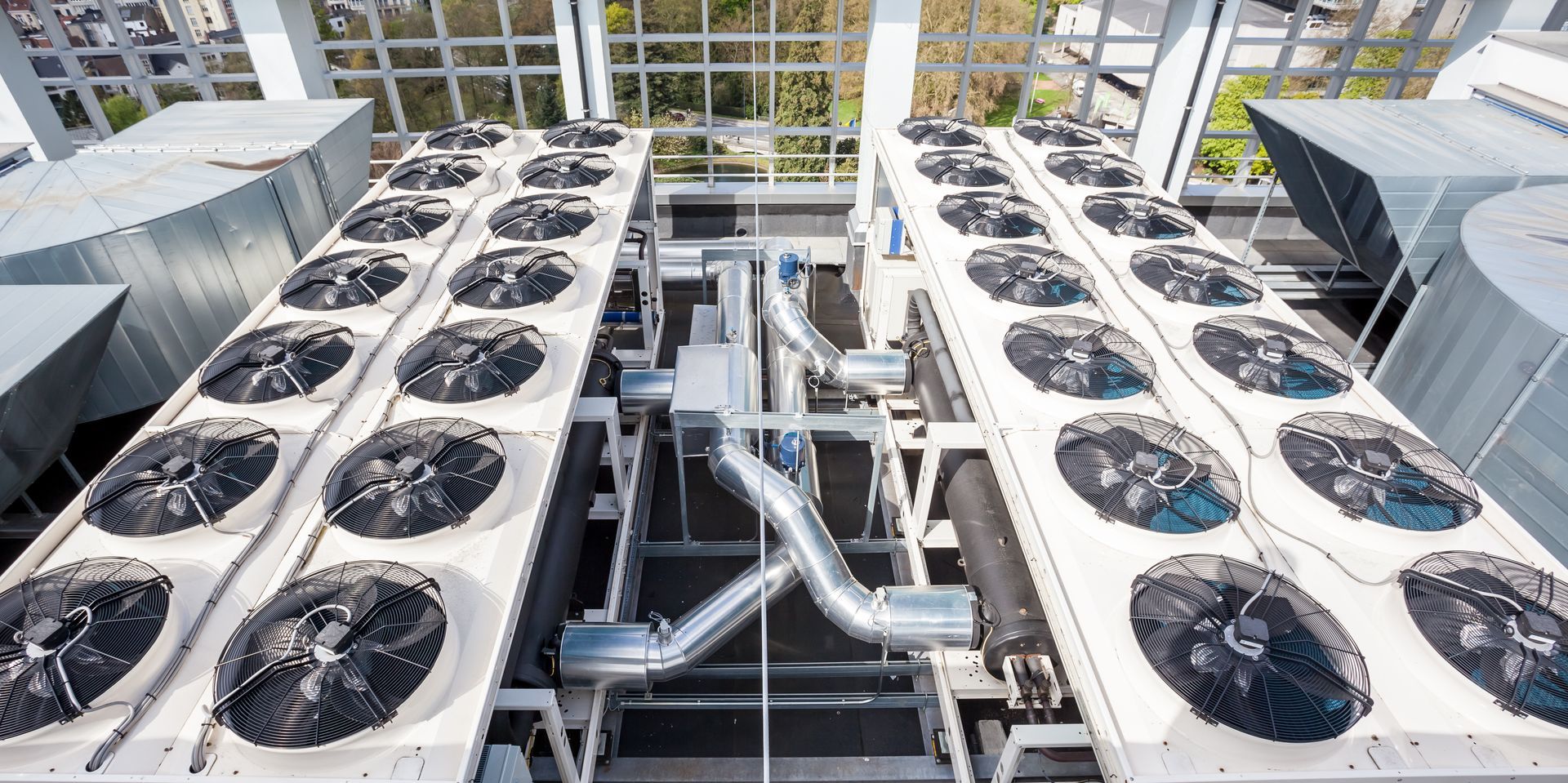 Two large industrial HVAC units with multiple black fans arranged in rows on top. Two large industrial HVAC units with multiple black fans arranged in rows on top.