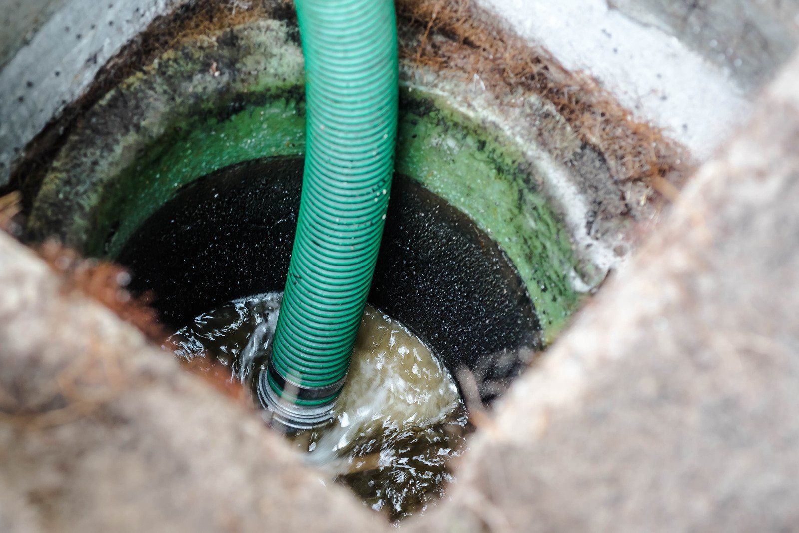 A man is fixing a hose in the dirt.