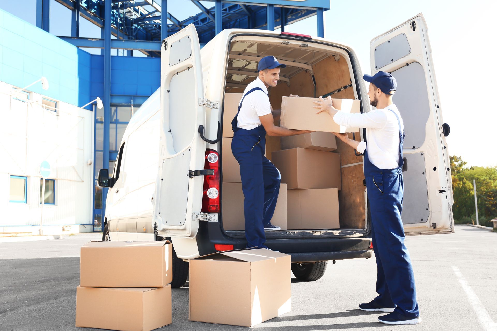 two delivery men are loading boxes into a van .