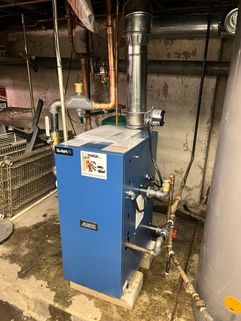 Blue boiler in a basement, with copper pipes, a silver vent, and a water tank.