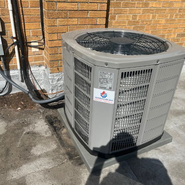 Outdoor air conditioning unit against a brick wall, with power cables.