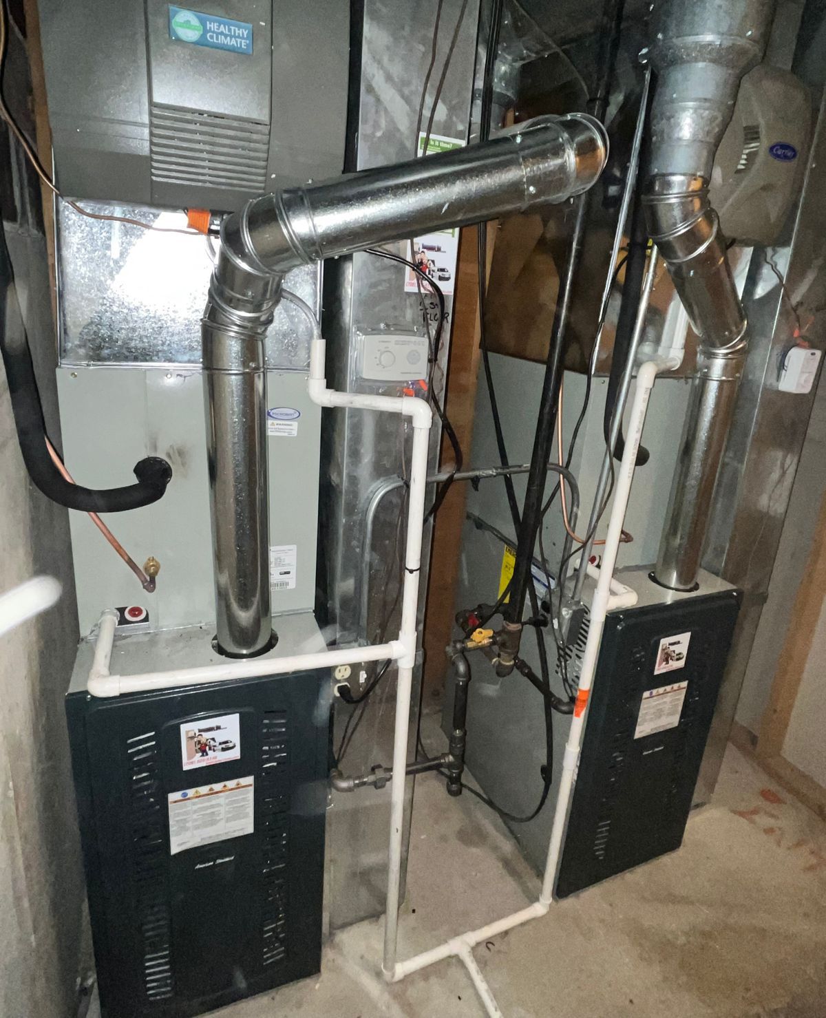 Two furnaces with ductwork in a basement setting.