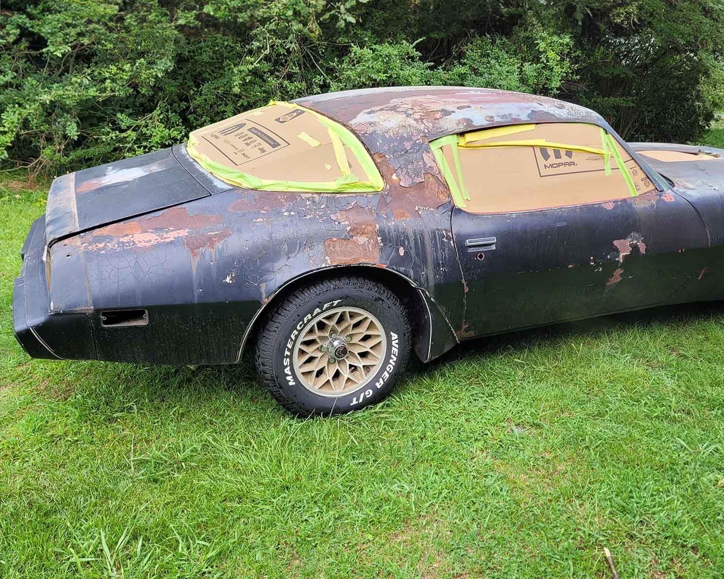 A black car is sitting on top of a lush green field.