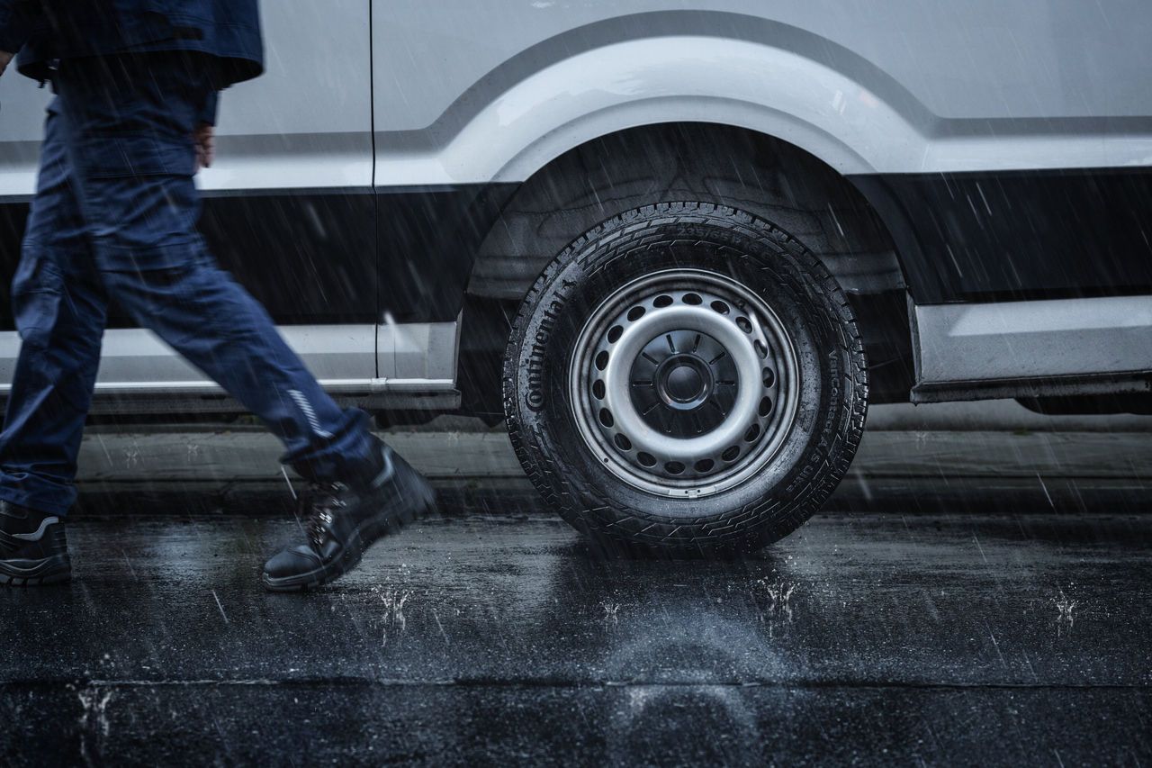 Person Walking Past a Van in the Rain — Cairns Tyre Specialists In Cairns City, QLD