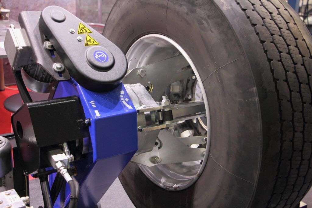 A Tire Machine Working on a Large Truck Tire; Blue and Silver Machinery — Cairns Tyre Specialists In Cairns City, QLD