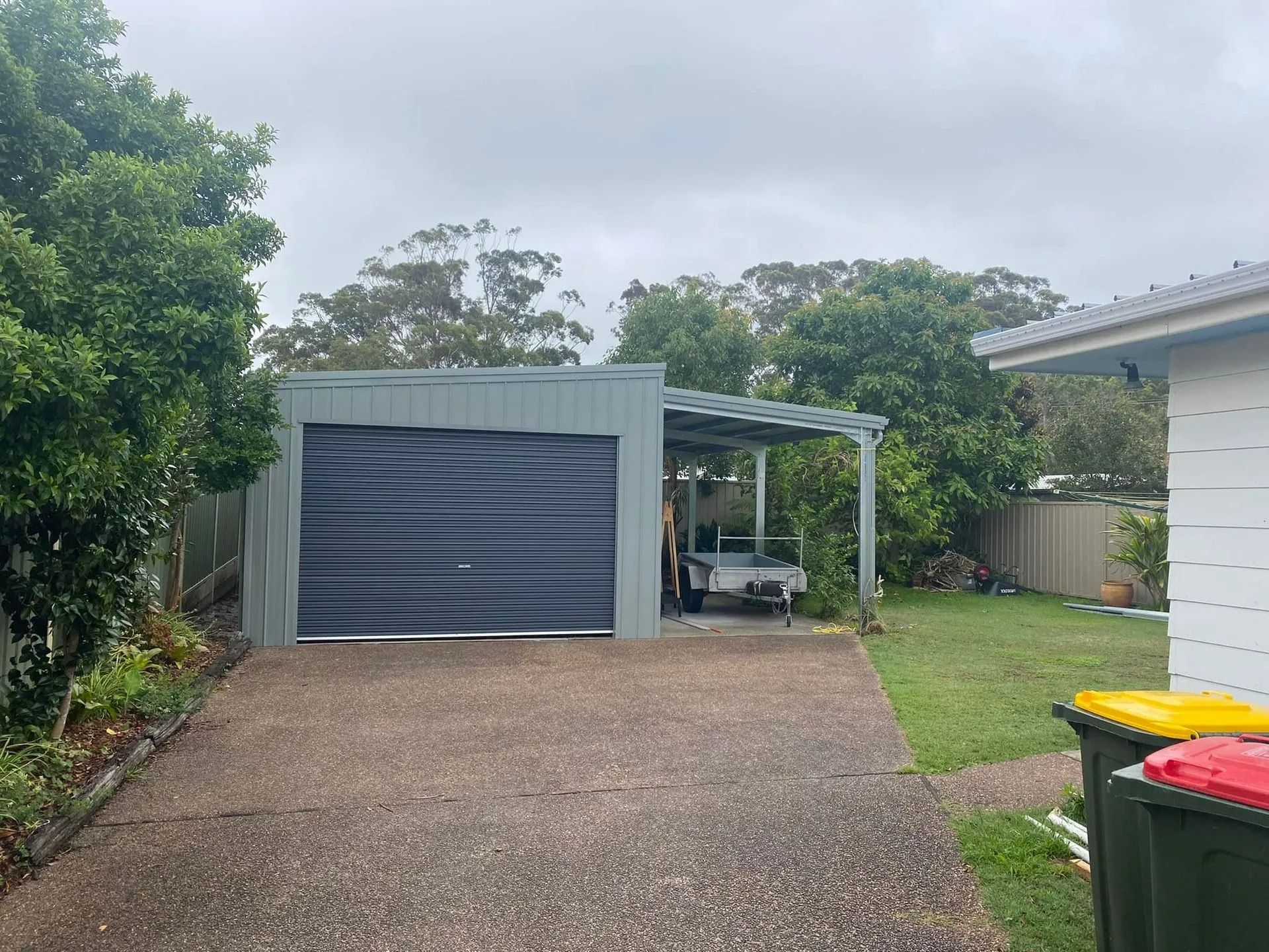 Garage with Attached Carport, Driveway, and Lawn Under a Cloudy Sky — Fair Dinkum Builds Port Stephens in Bobs Farm, NSW