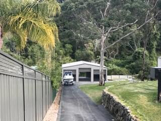 A White Shed with Three Bays Sits at The End of A Paved Driveway — Fair Dinkum Builds Port Stephens in New Castle, NSW