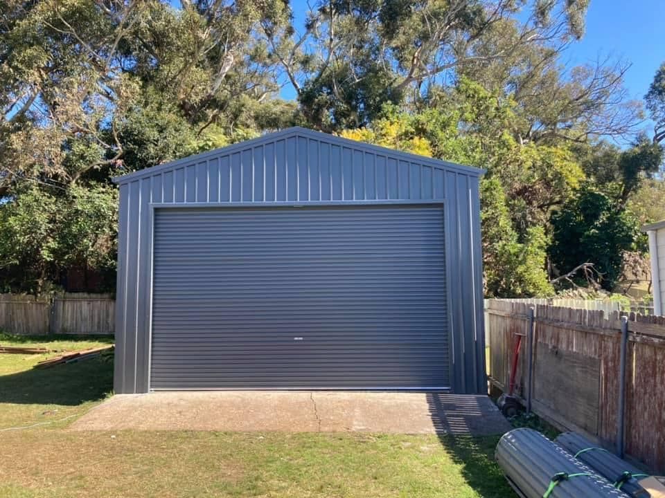 Gray Metal Garage with A Closed Roller Door, in A Backyard — Fair Dinkum Builds Port Stephens in Bobs Farm, NSW