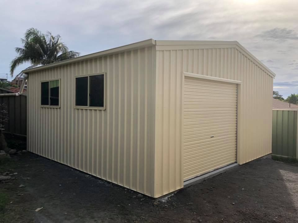 Beige Metal Shed with Roller Door and Two Windows, Set on Gravel — Fair Dinkum Builds Port Stephens in Hunter Valley, NSW