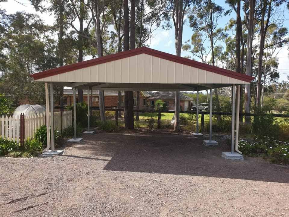 A Carport with A Red Roof, Cream Walls, and Metal Supports Stands — Fair Dinkum Builds Port Stephens in Bobs Farm, NSW