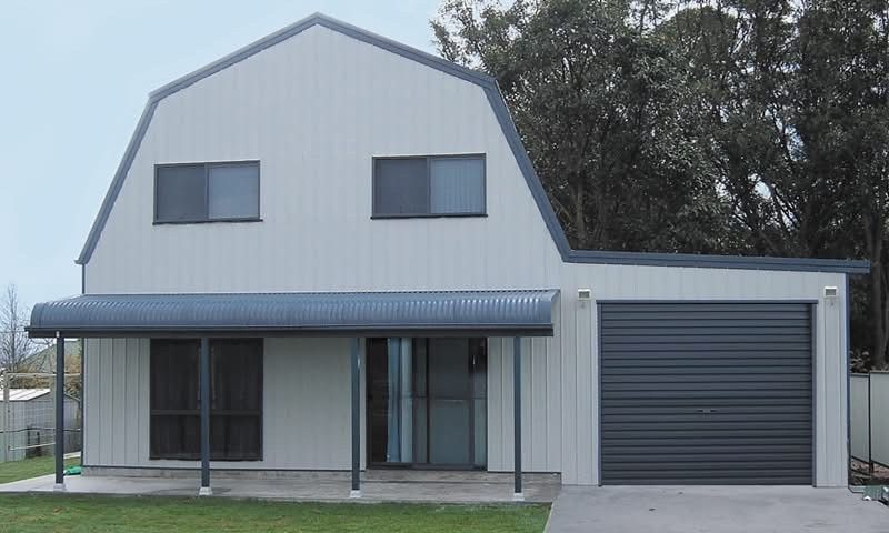 Two-story light gray barn-style house with attached garage, gray awning, and dark gray garage door.