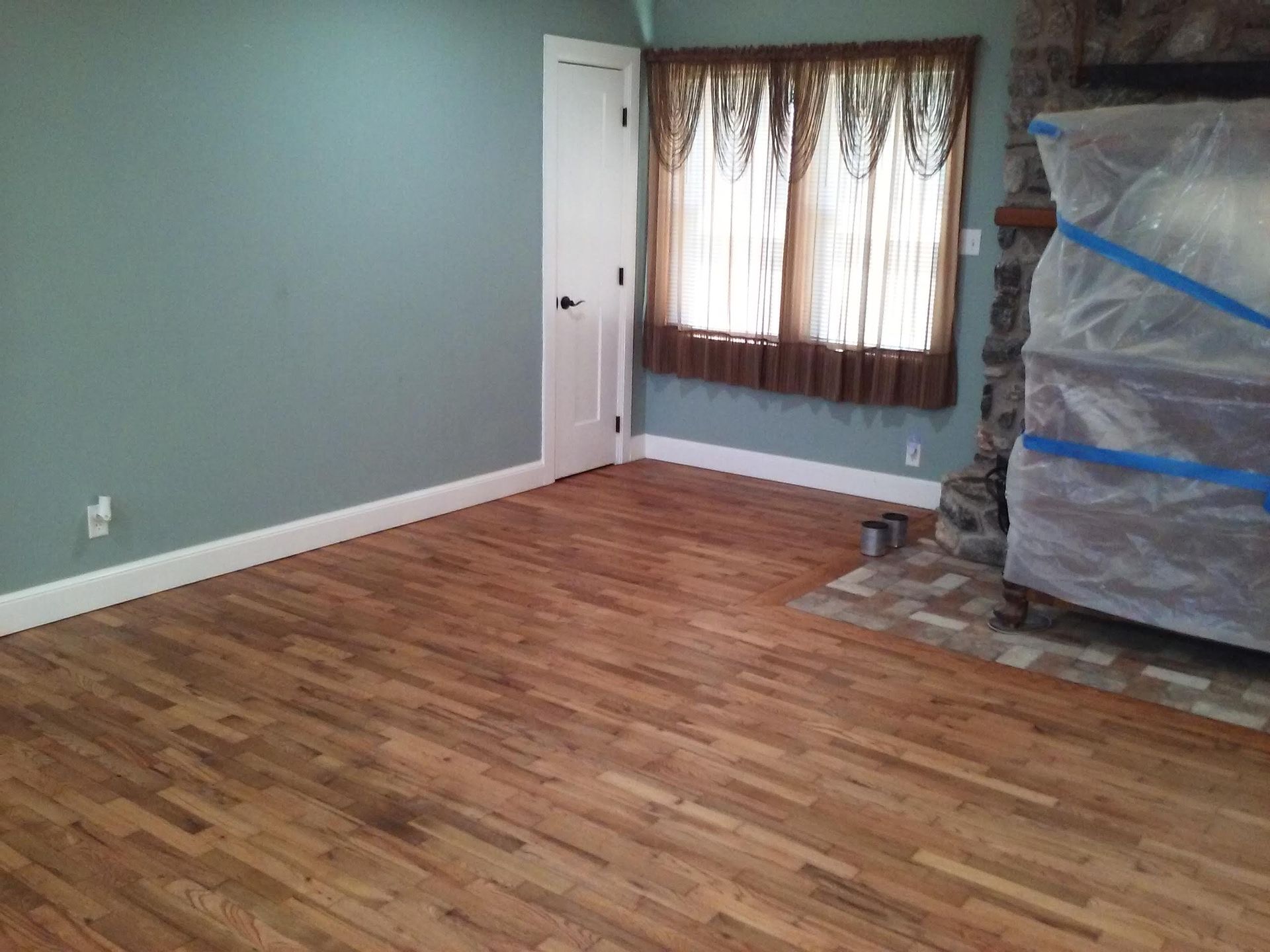 An empty living room with hardwood floors and a fireplace
