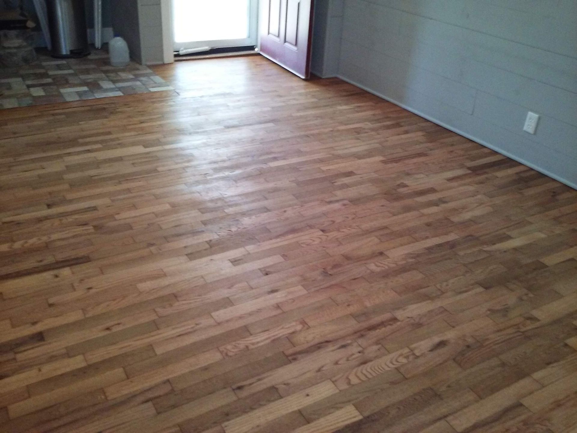 A room with a wooden floor and a purple door.