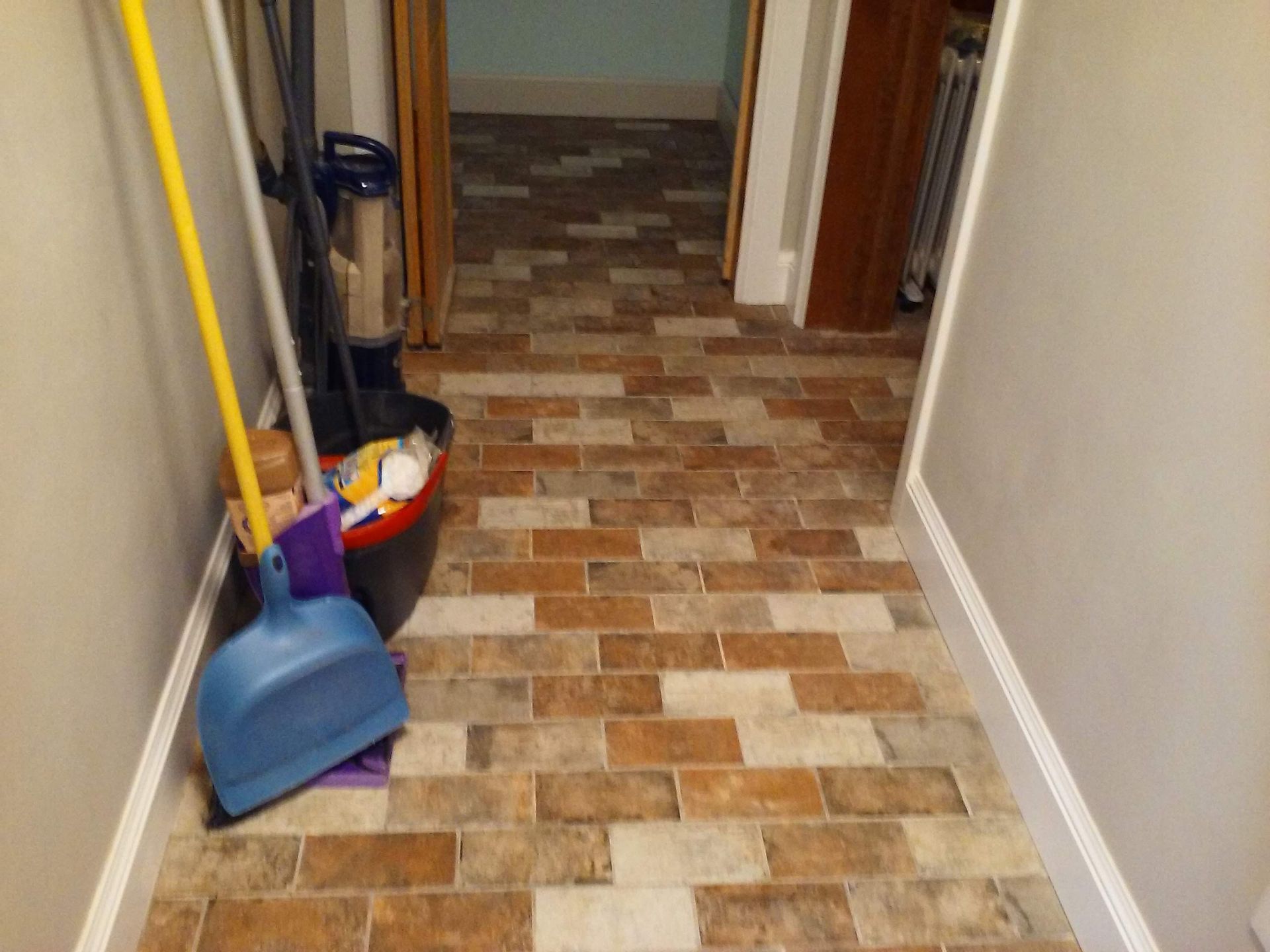 A hallway with a vacuum cleaner and a broom on the floor.