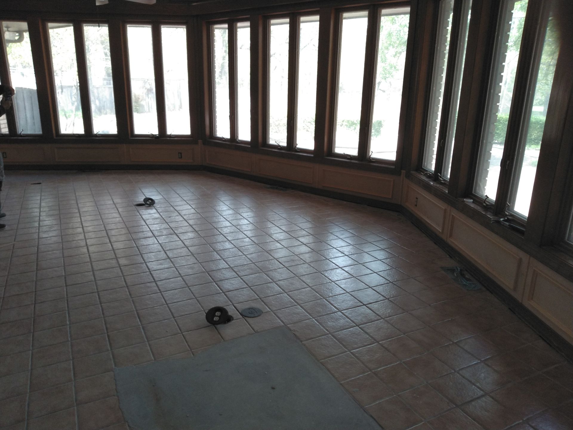 An empty room with lots of windows and tile floors