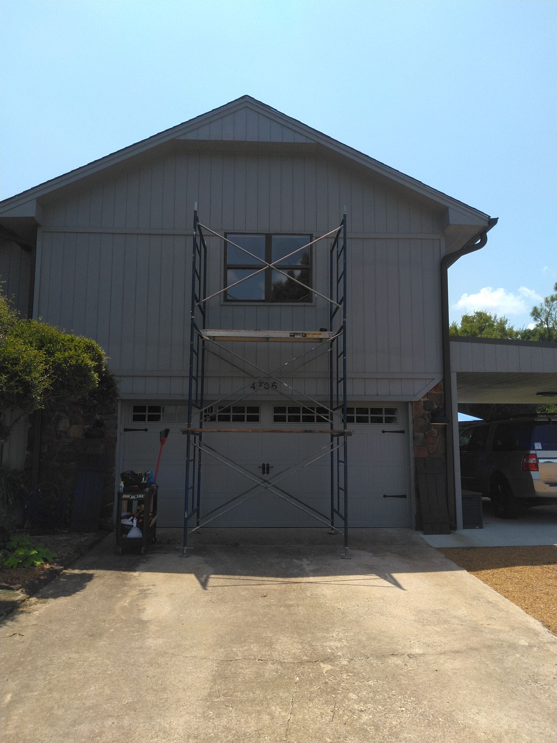 A house with a garage and a scaffolding in front of it.