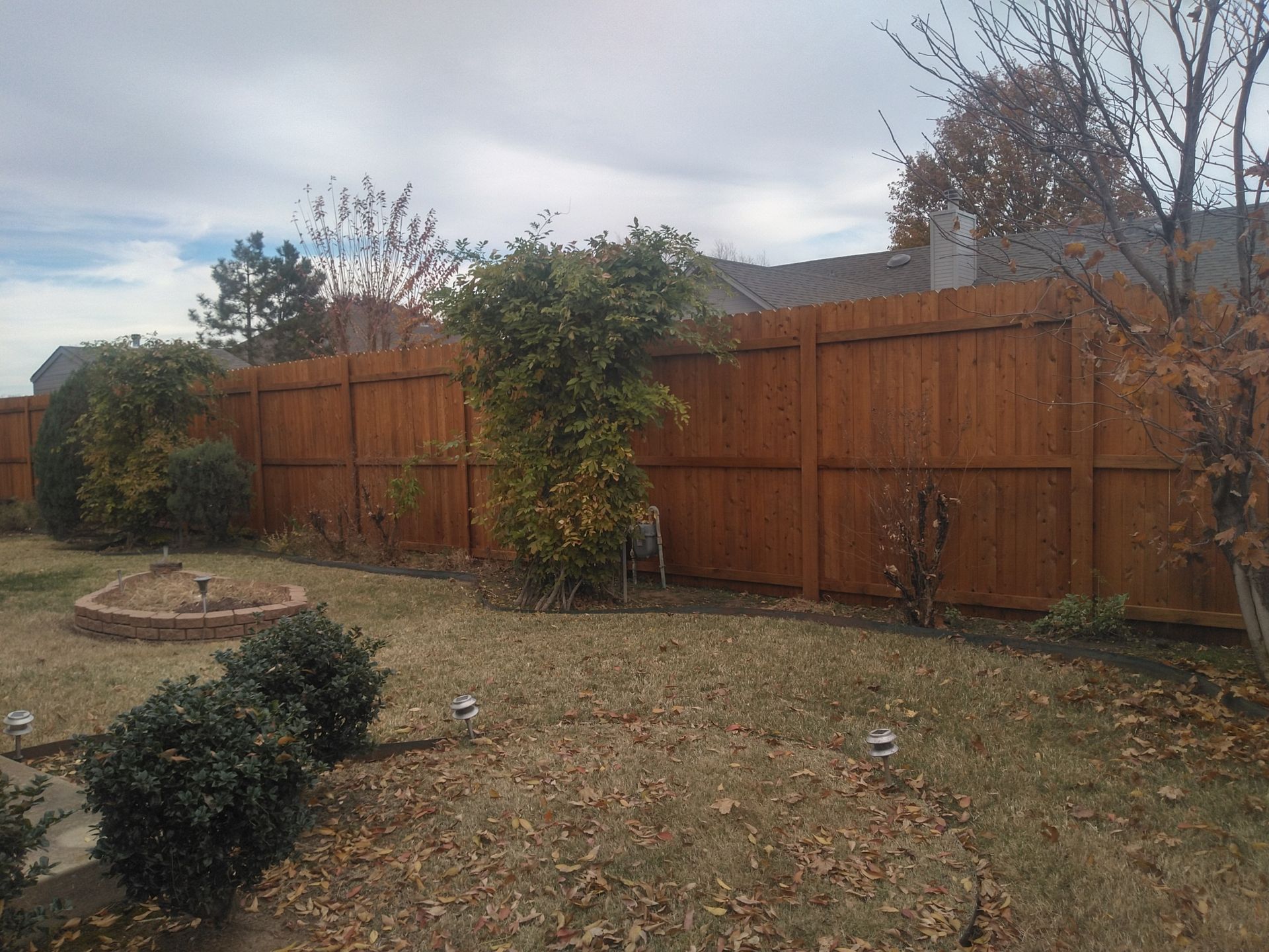 A backyard with a wooden fence and a fountain
