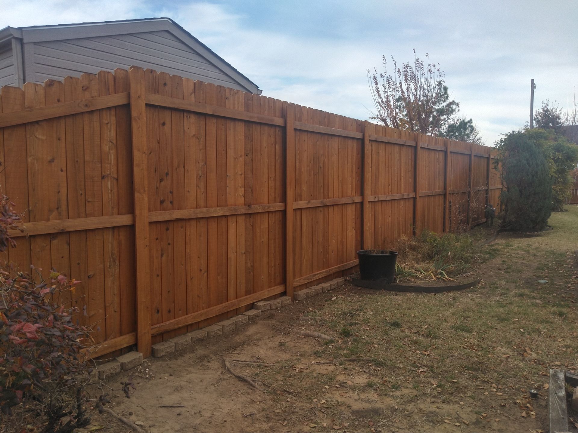 A wooden fence is in the backyard of a house.