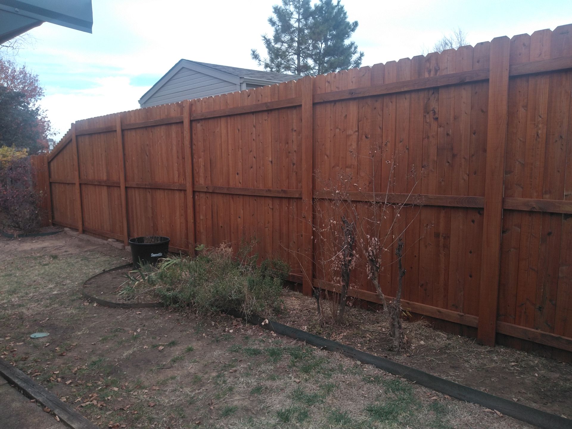 A wooden fence is in the backyard of a house.