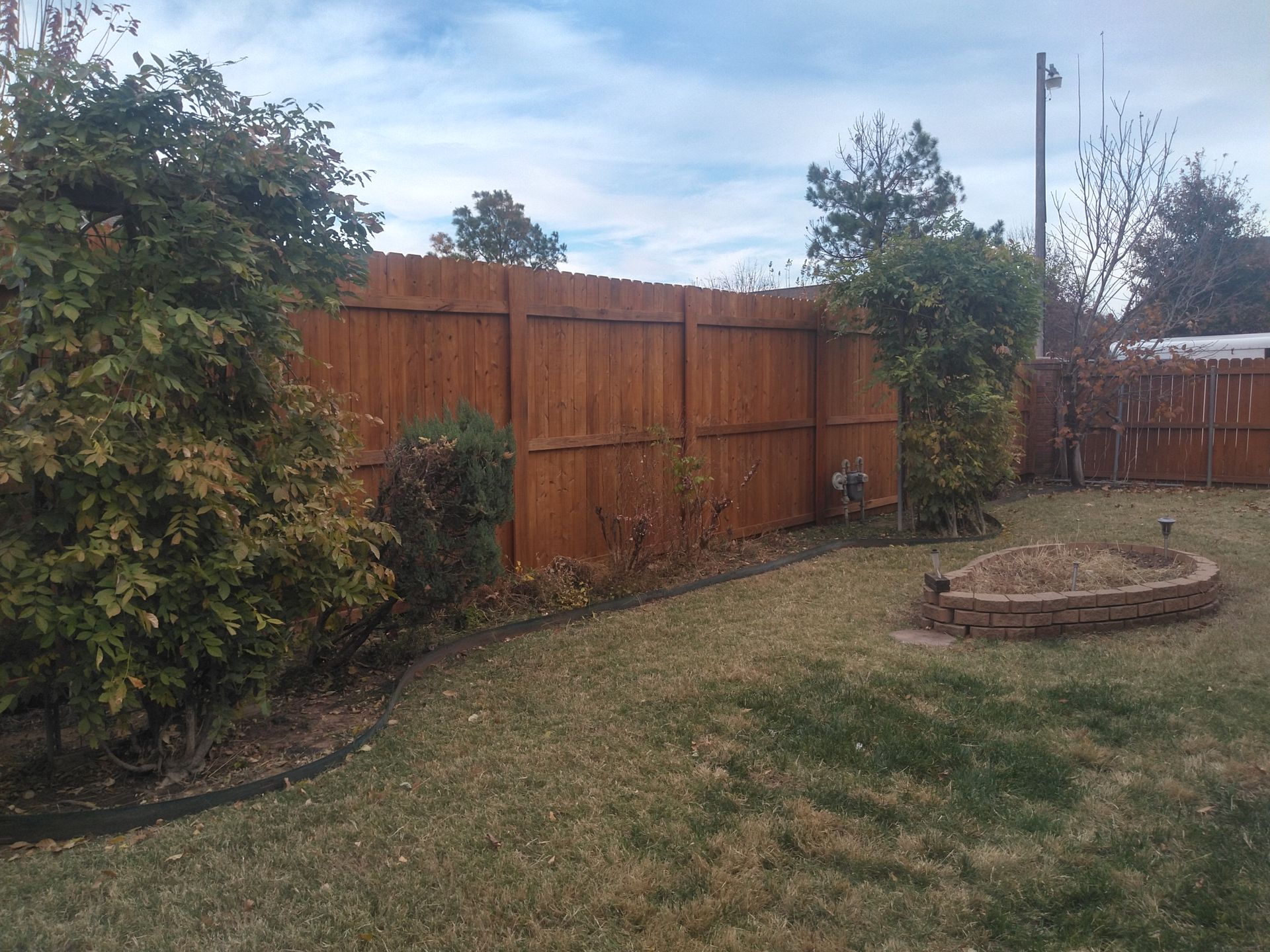 A backyard with a wooden fence and a fire pit.