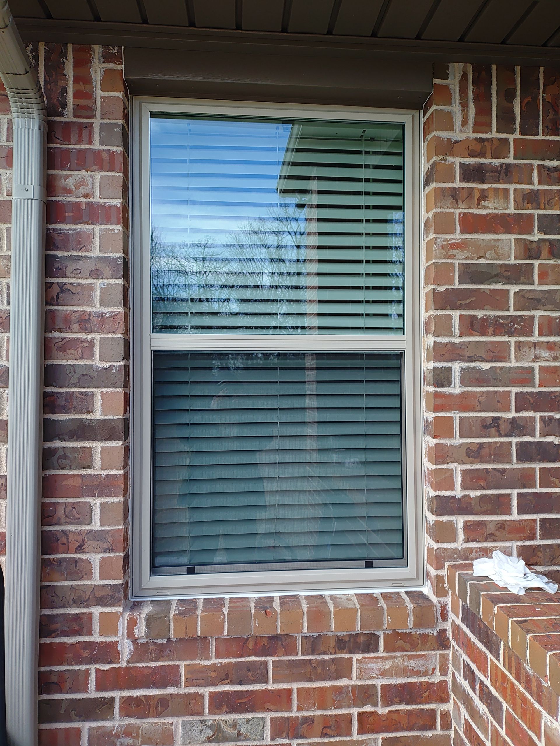A brick wall with a window and blinds on it