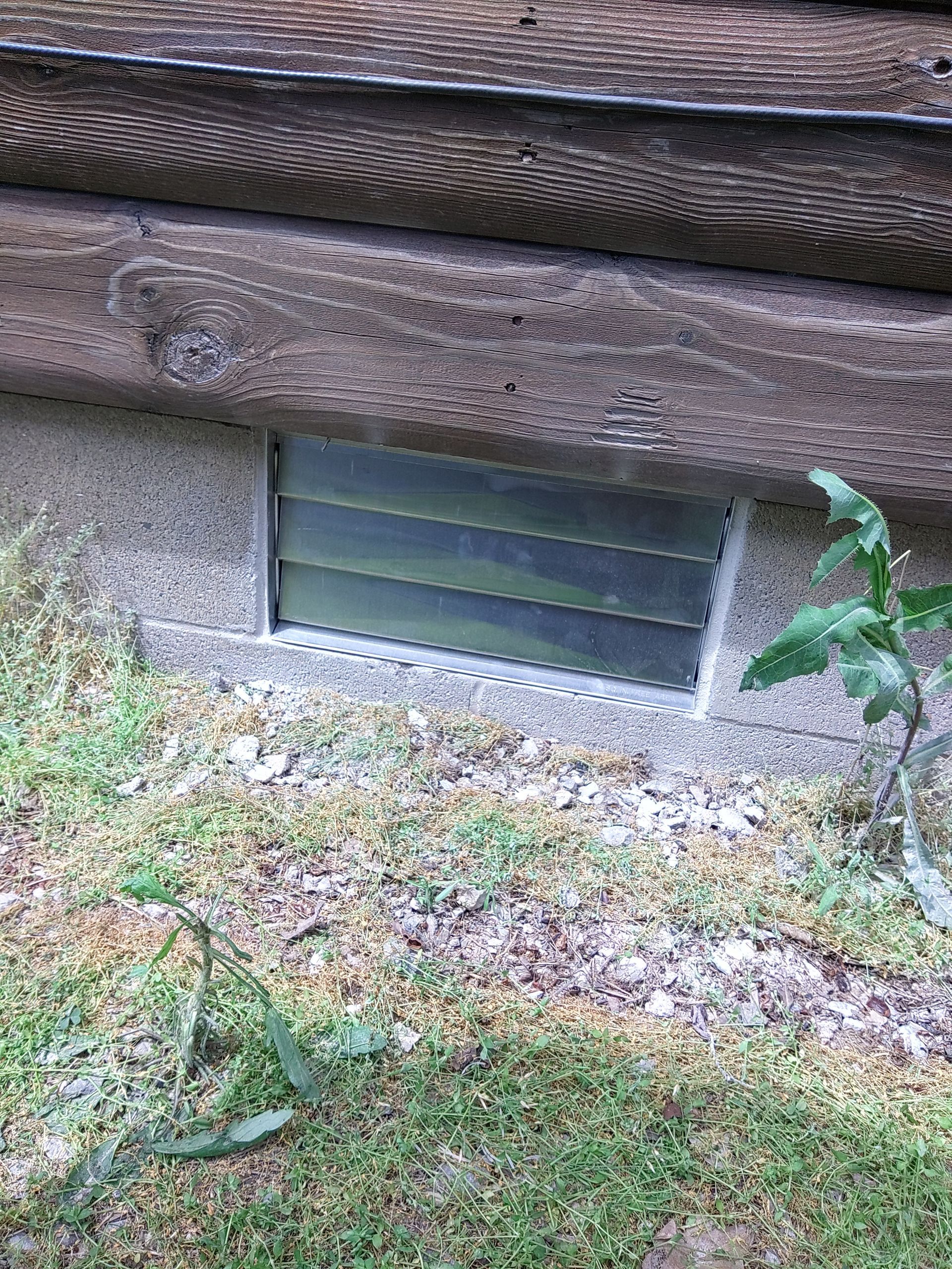 A window in the ground next to a wooden wall.