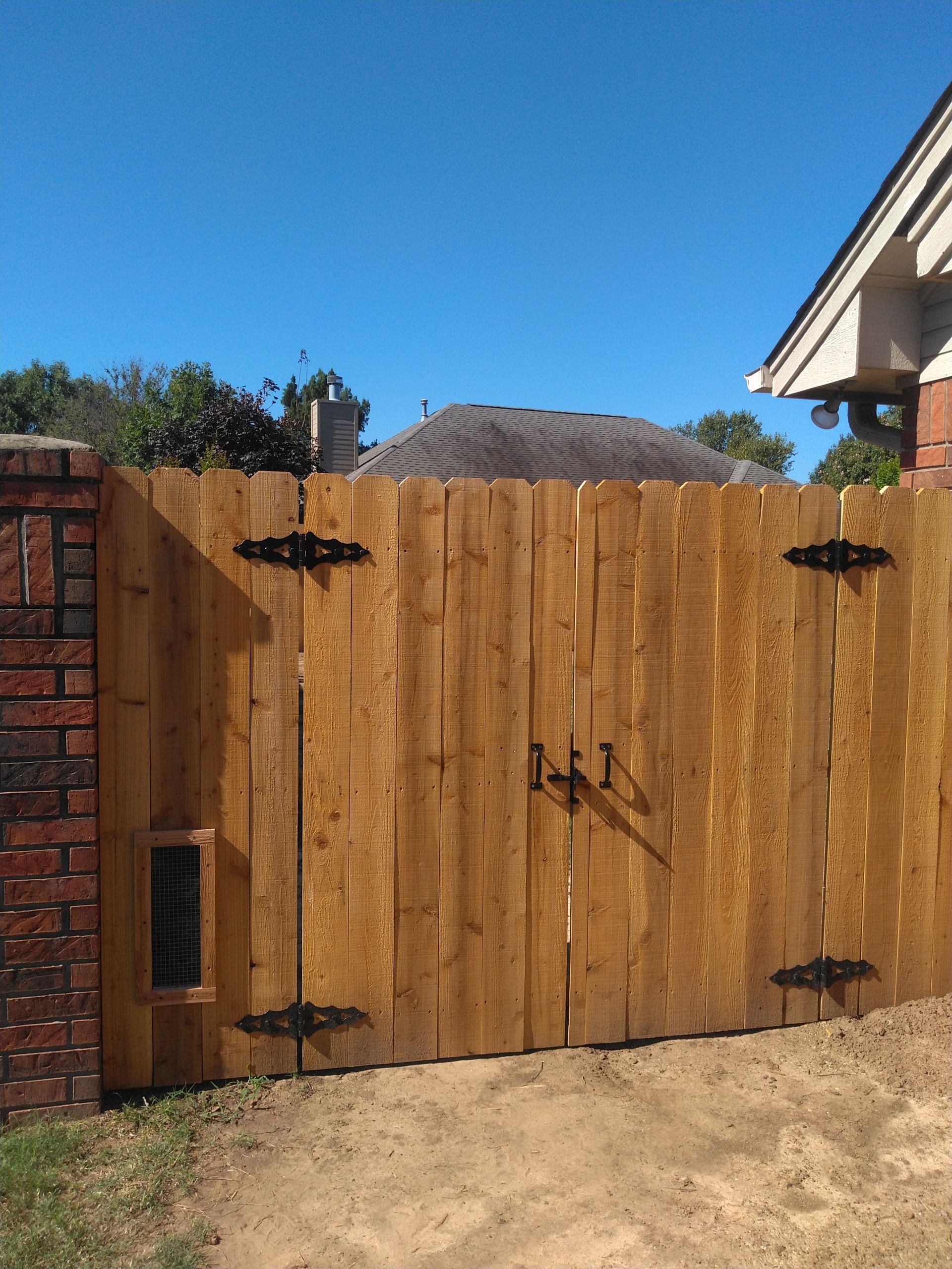 A wooden fence with a brick wall behind it