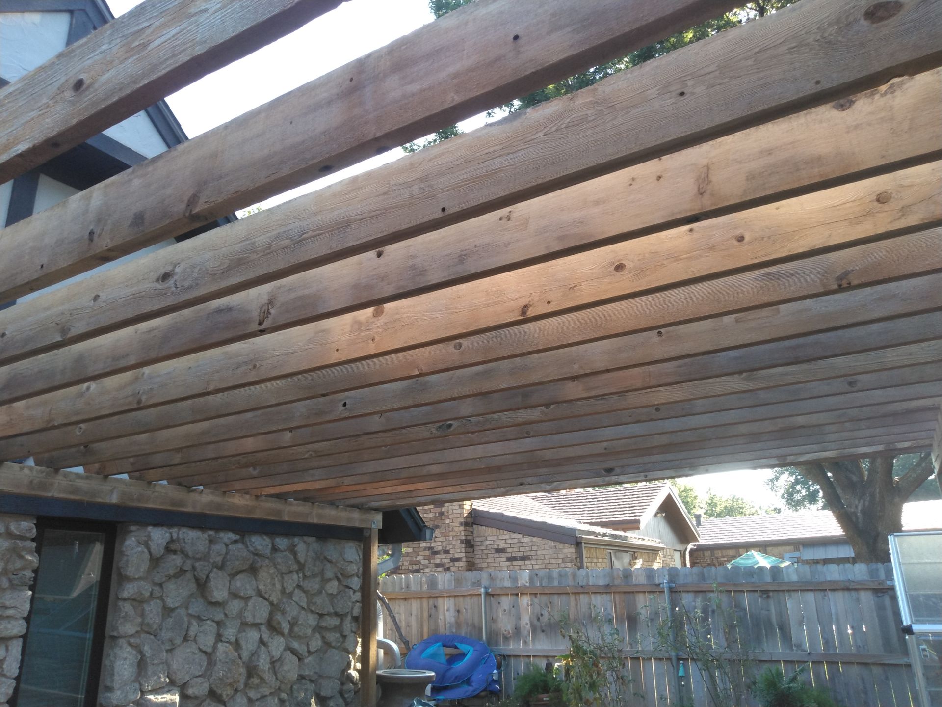 A wooden pergola with a fence in the background