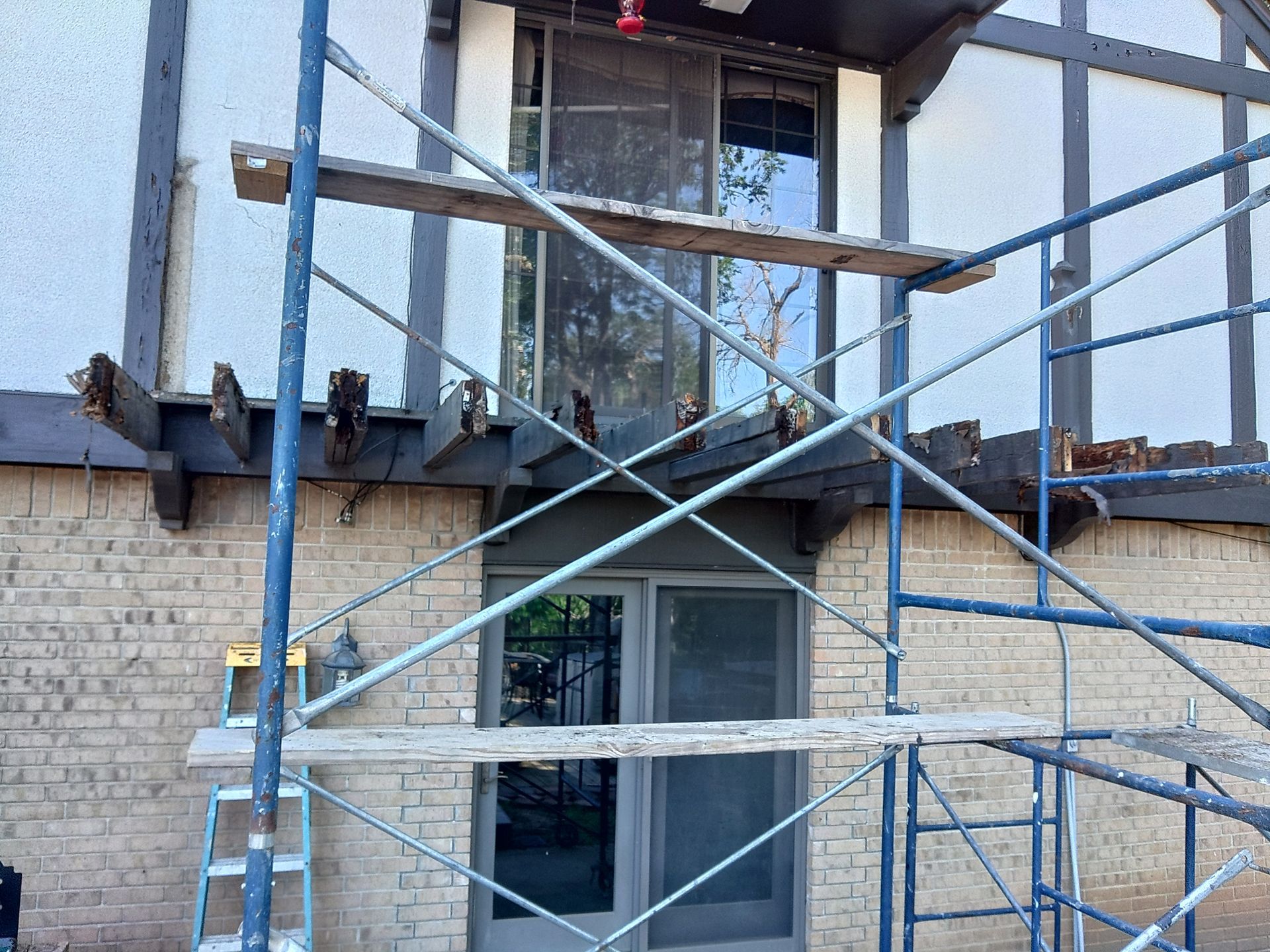 A blue scaffolding is sitting in front of a brick building.