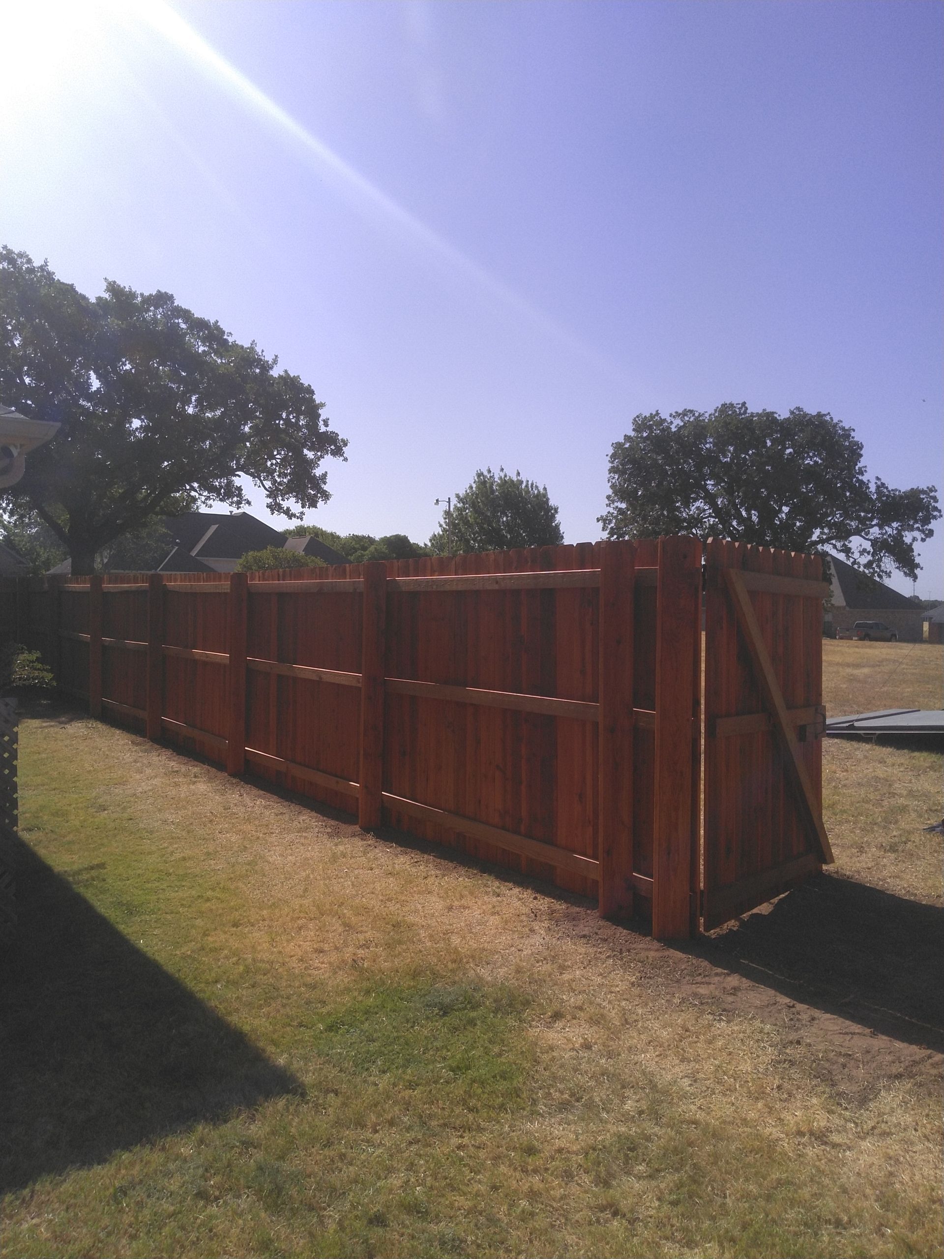 A wooden fence is in the middle of a grassy field