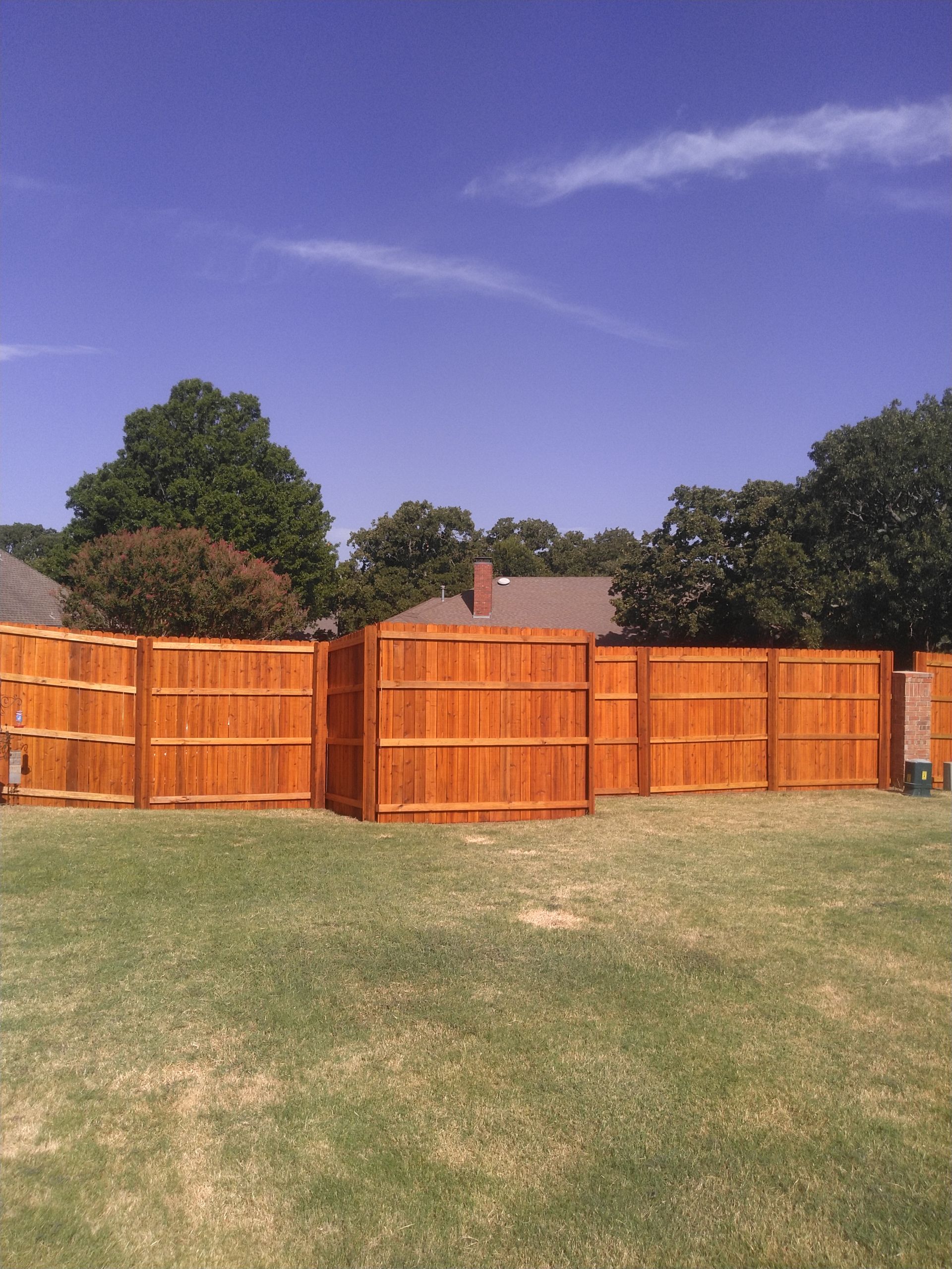 A wooden fence is in the middle of a lush green field.