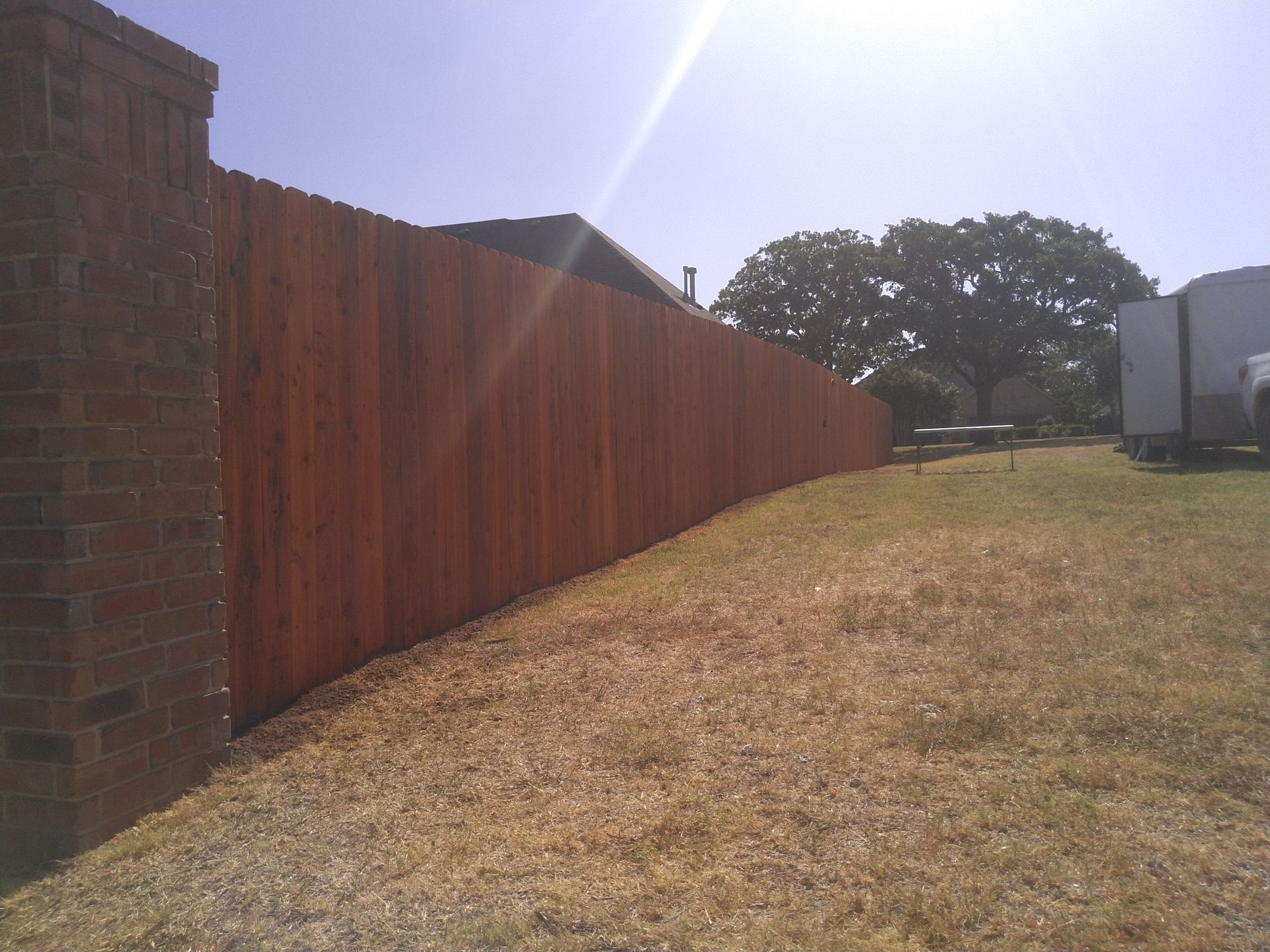 A wooden fence surrounds a brick wall in a backyard