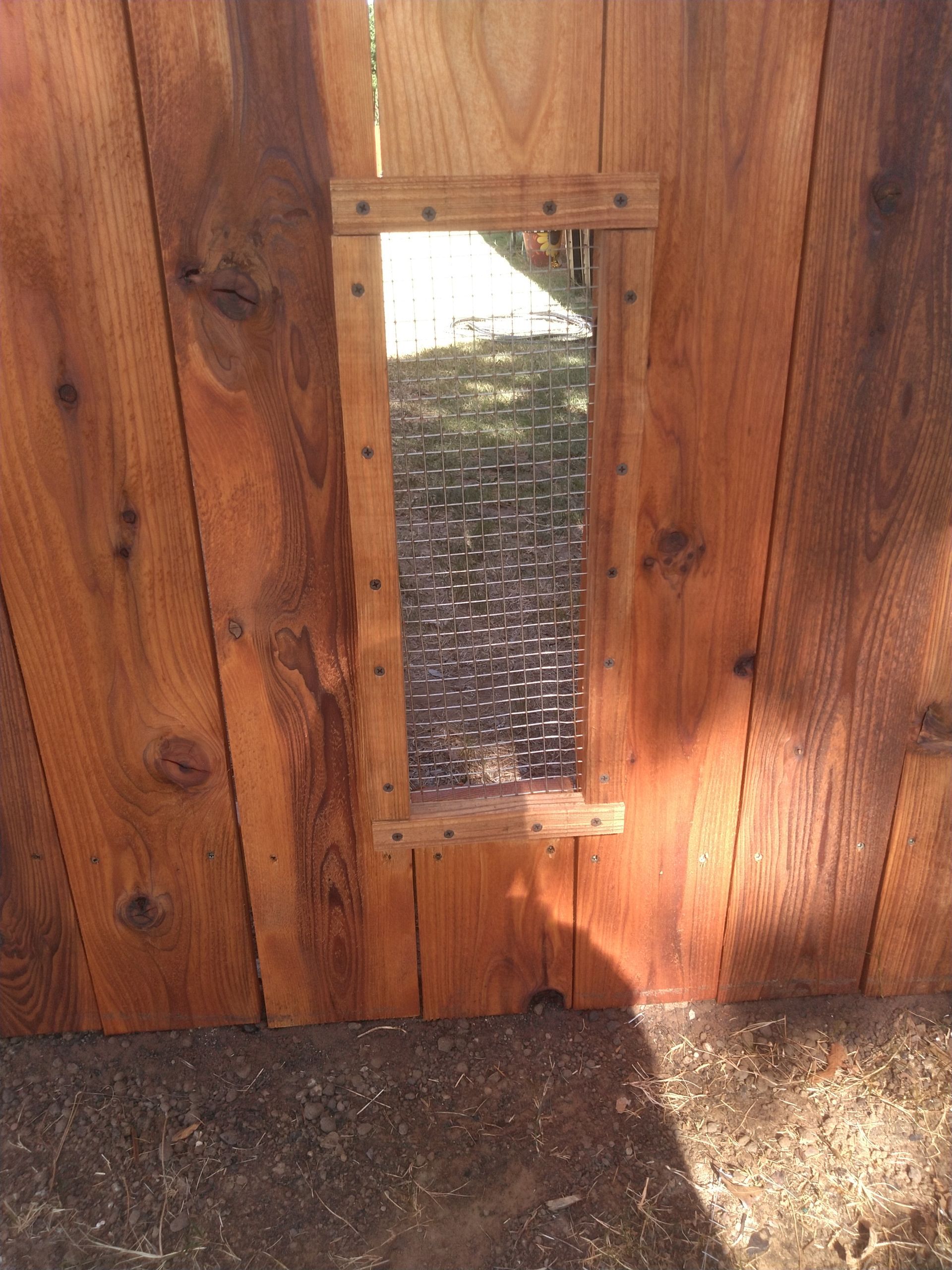 A wooden fence with a small window in the middle of it.
