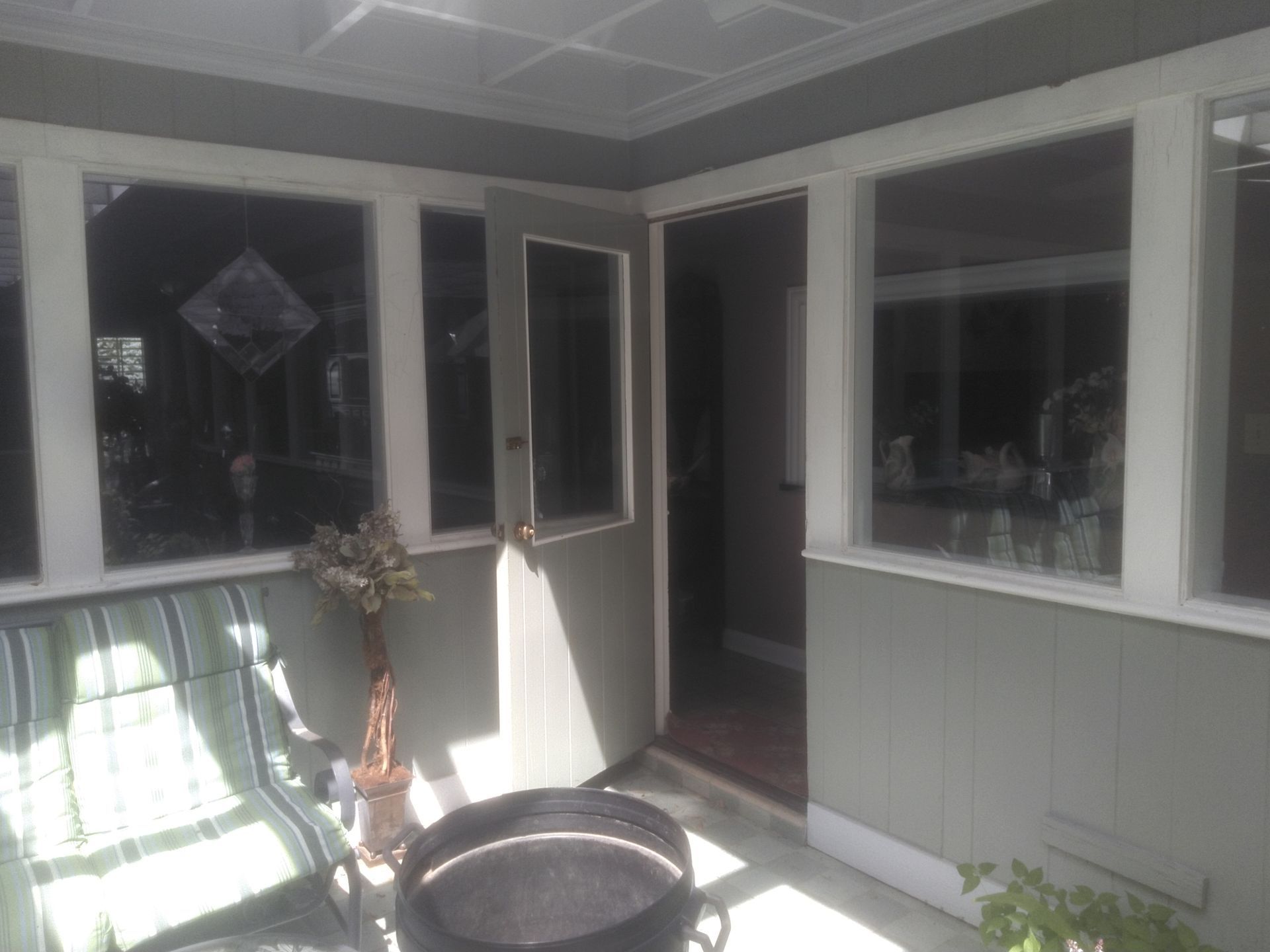 A screened in porch with a lot of windows and a fire pit.