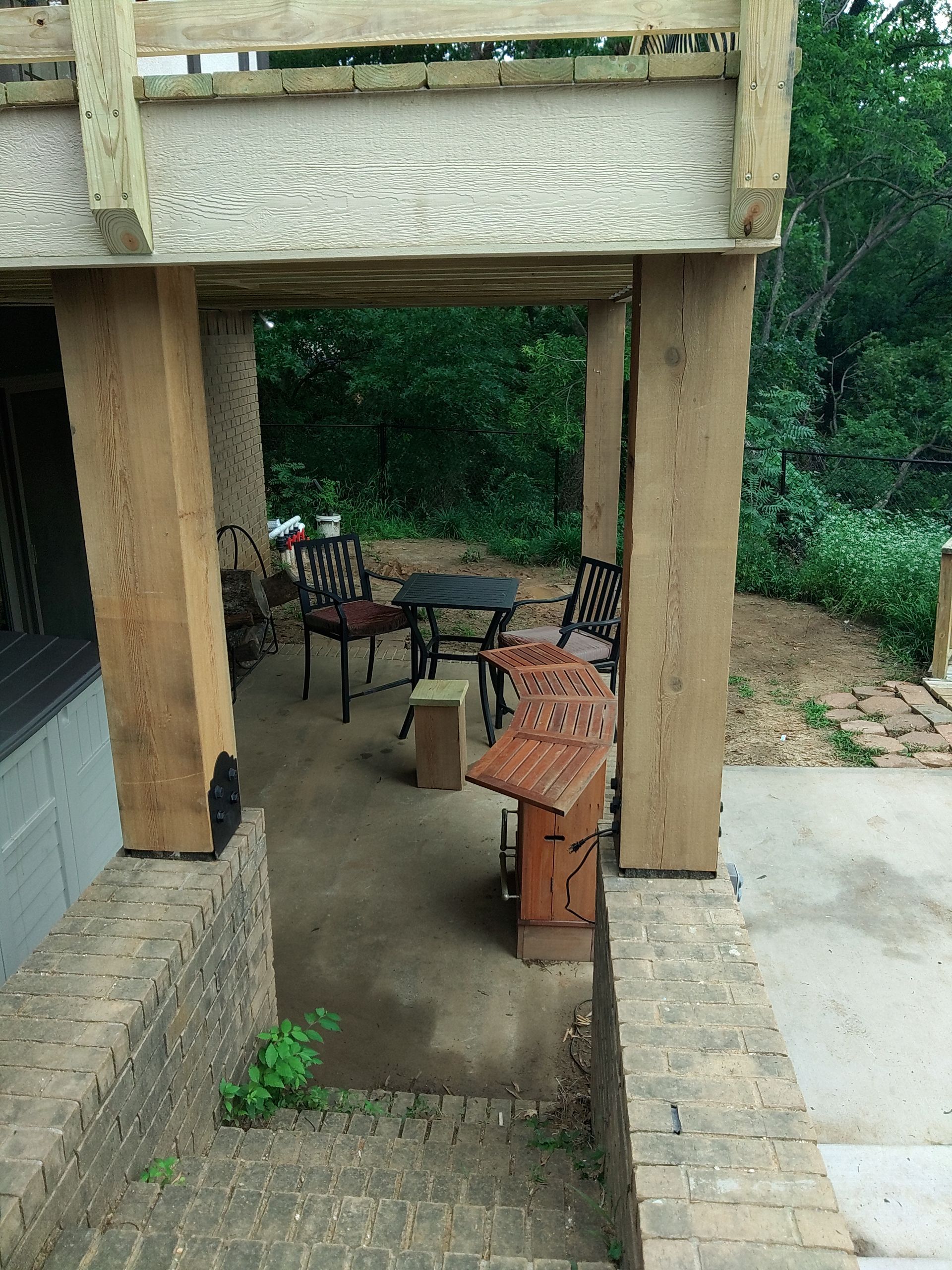 A patio with a table and chairs under a wooden structure